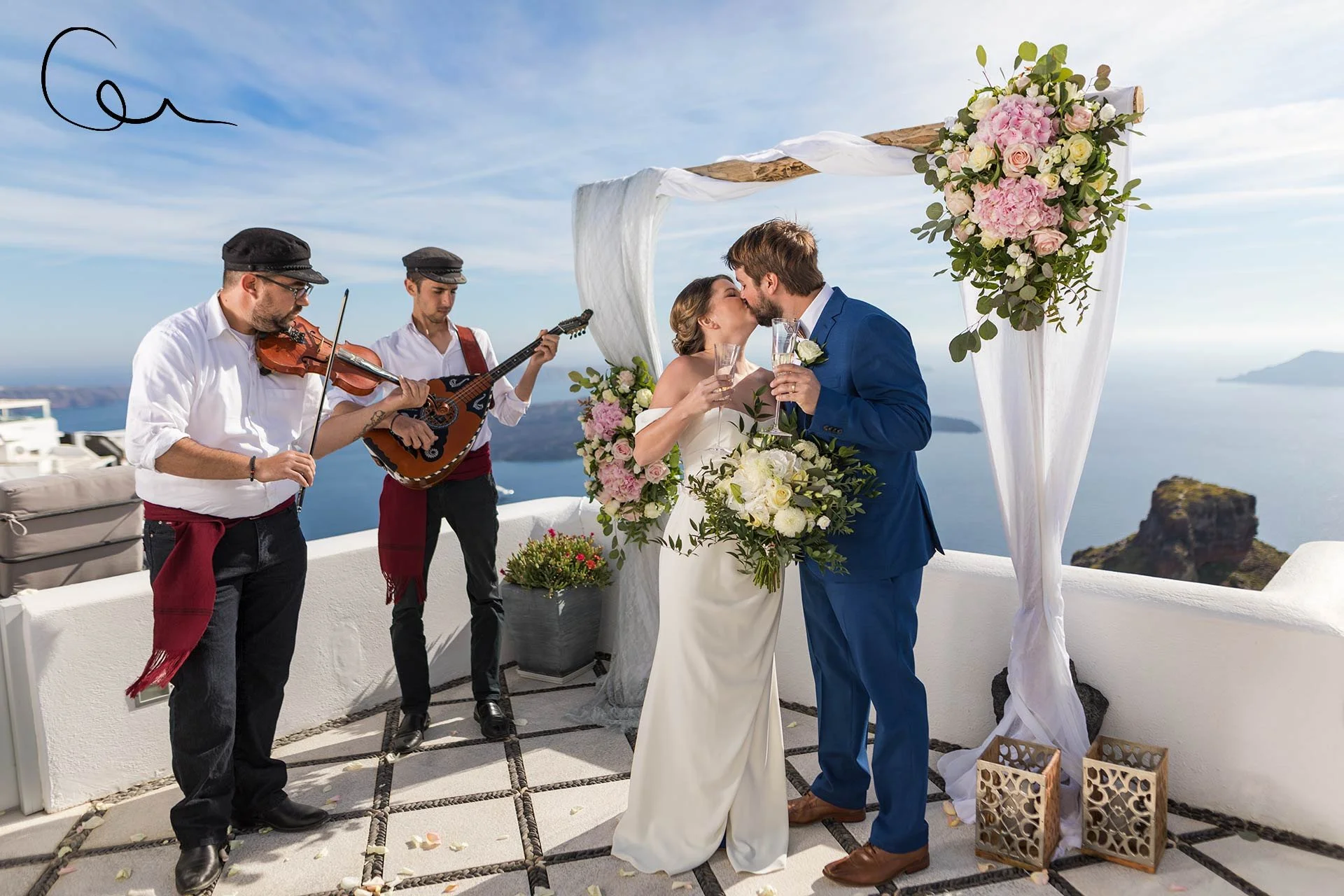 Santorini wedding photography golden‑hour portrait on the pier at Amoudi Bay with fishermen houses, reflective water and warm sunset tones.