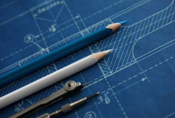 Blue technical blueprint with two pencils and drafting tools.
