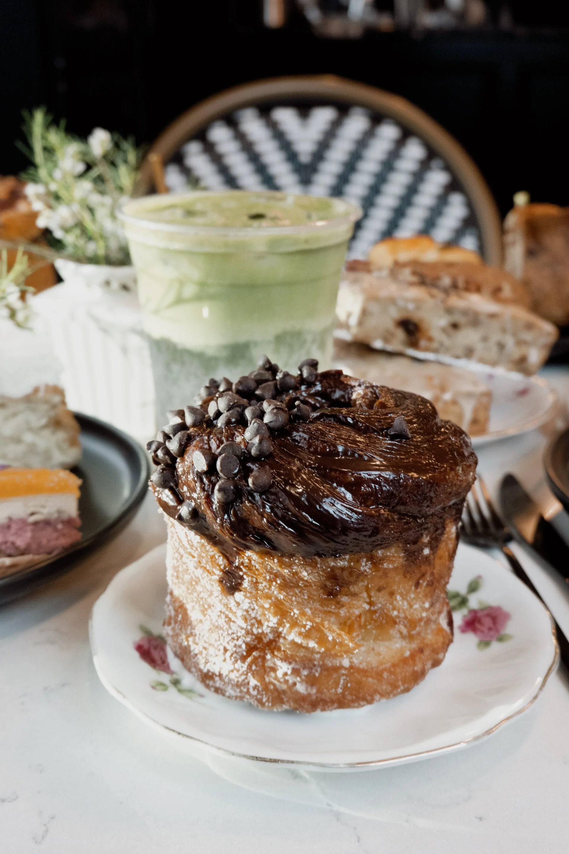 Chocolate chip cruffin pastry on plate with matcha latte.