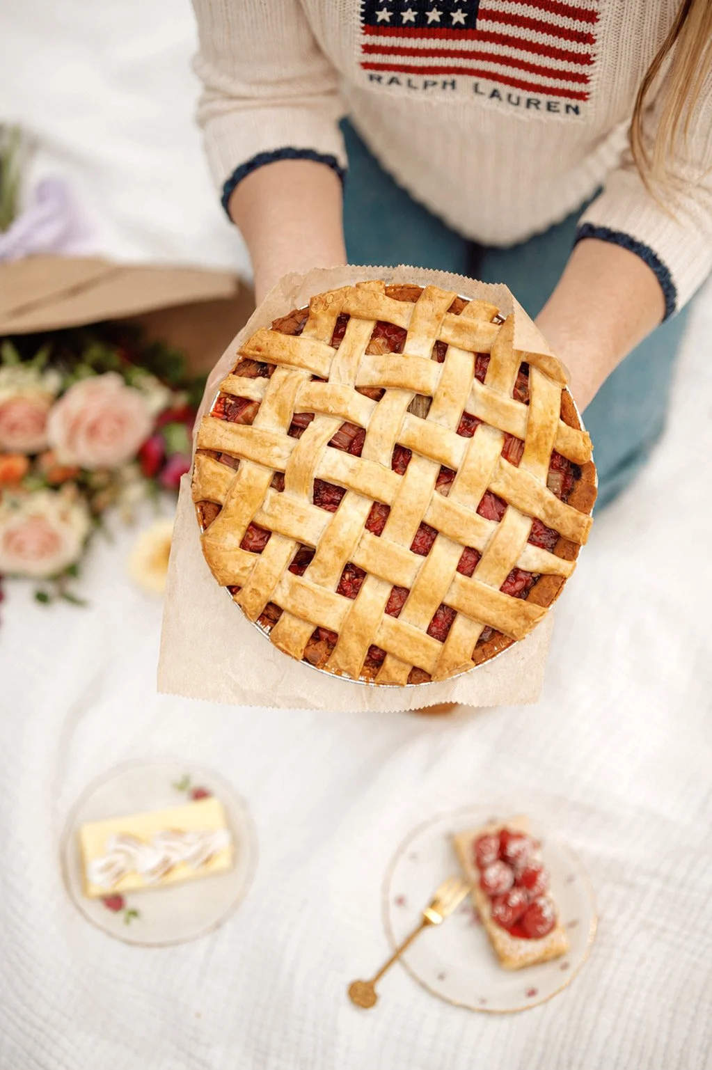 Strawberry rhubard pie at a picnic with flowers, cupcakes, and lemon bars.