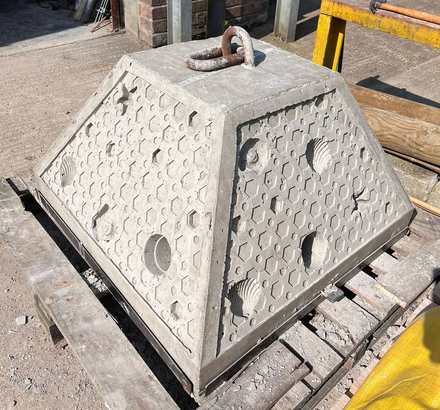 A concrete sinker weight covered in honeycomb and animal textures, on a pallet