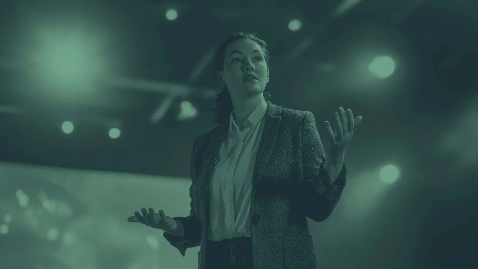 A woman presents on stage at a large conference.