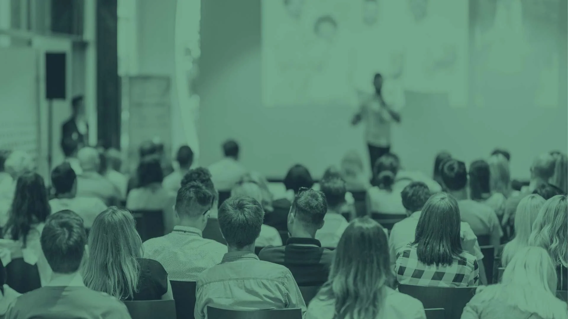 An audience listens to a speaker at a conference.