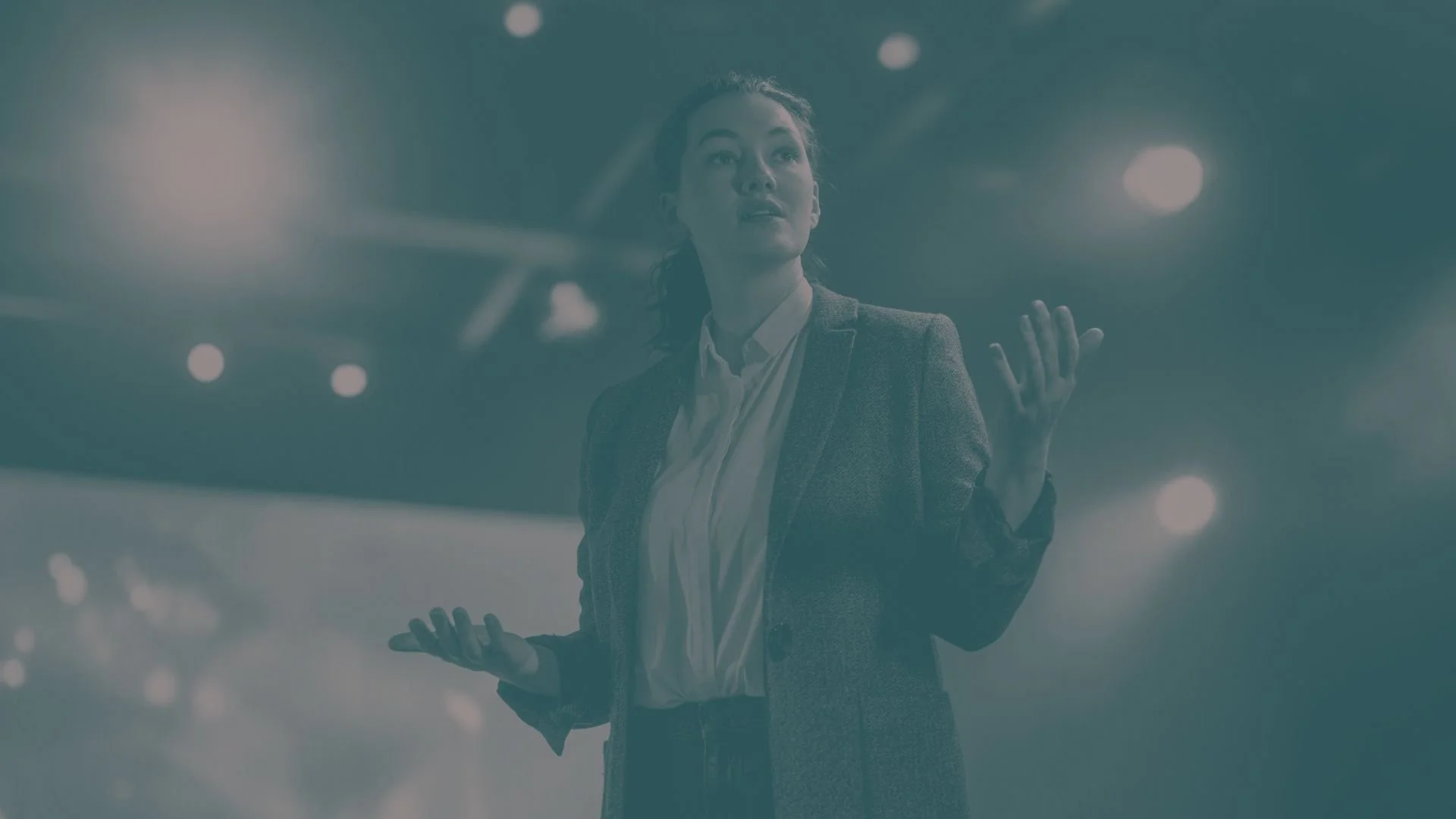 A woman presents on stage at a large conference.