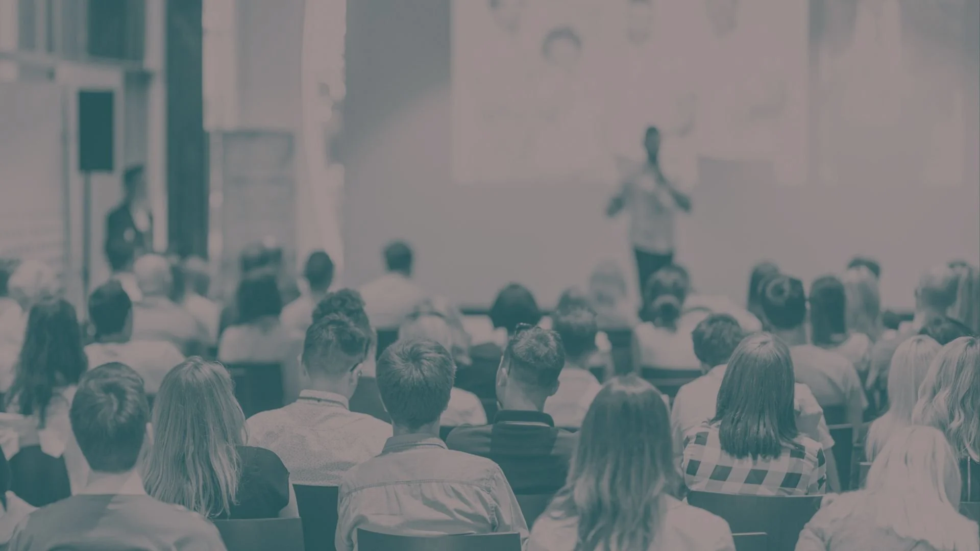 An audience listens to a speaker at a conference.