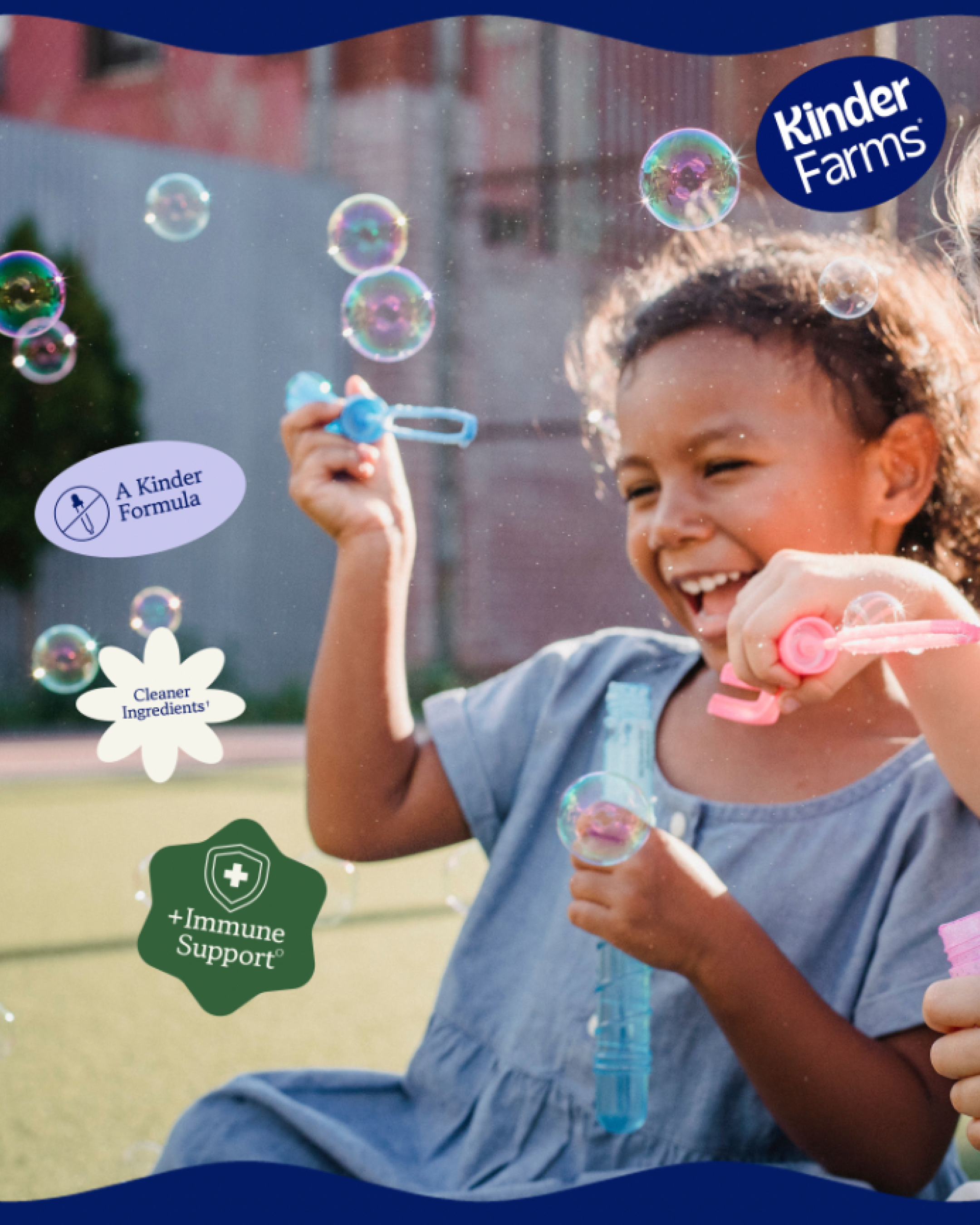 A child with curly hair smiling and playing with soap bubbles outdoors, holding a bubble wand with bubbles floating around, with labels indicating 'A Kinder Formula,' 'Kinder Farms,' and '+Immune Support'.