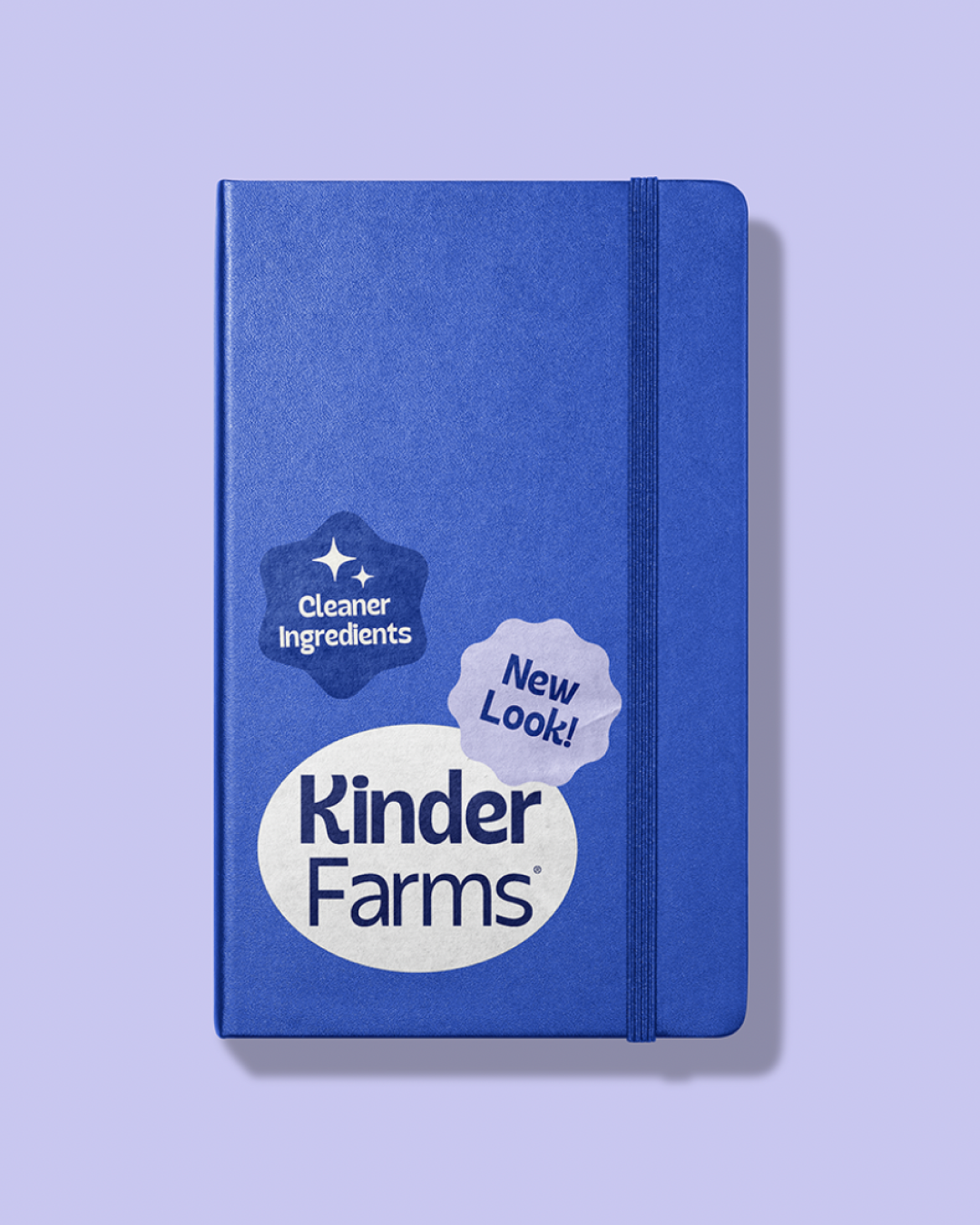 A blue Kinder Farms notebook with a light purple background, featuring a label that says "Cleaner Ingredients" and "New Look!"