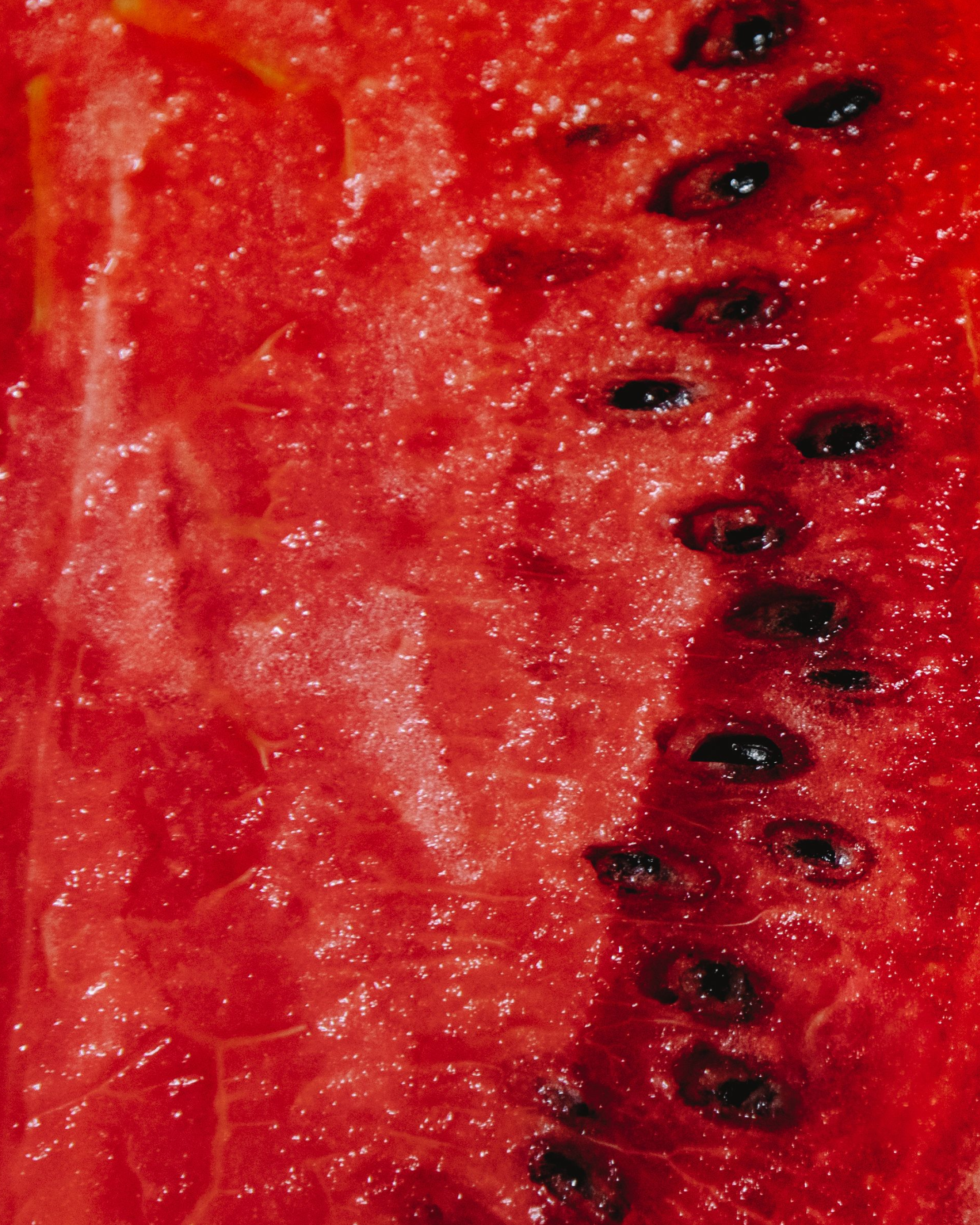 Close-up view of a fresh, sliced watermelon with bright red flesh and black seeds.