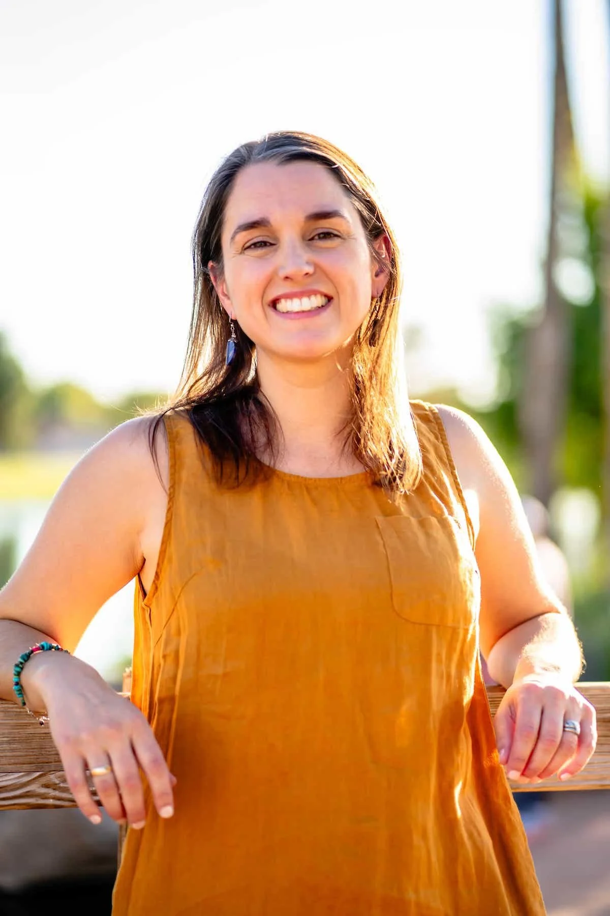 Close up of Therapist Tara Nicotra Clemente outside with arms on fence and blurred sunlight background