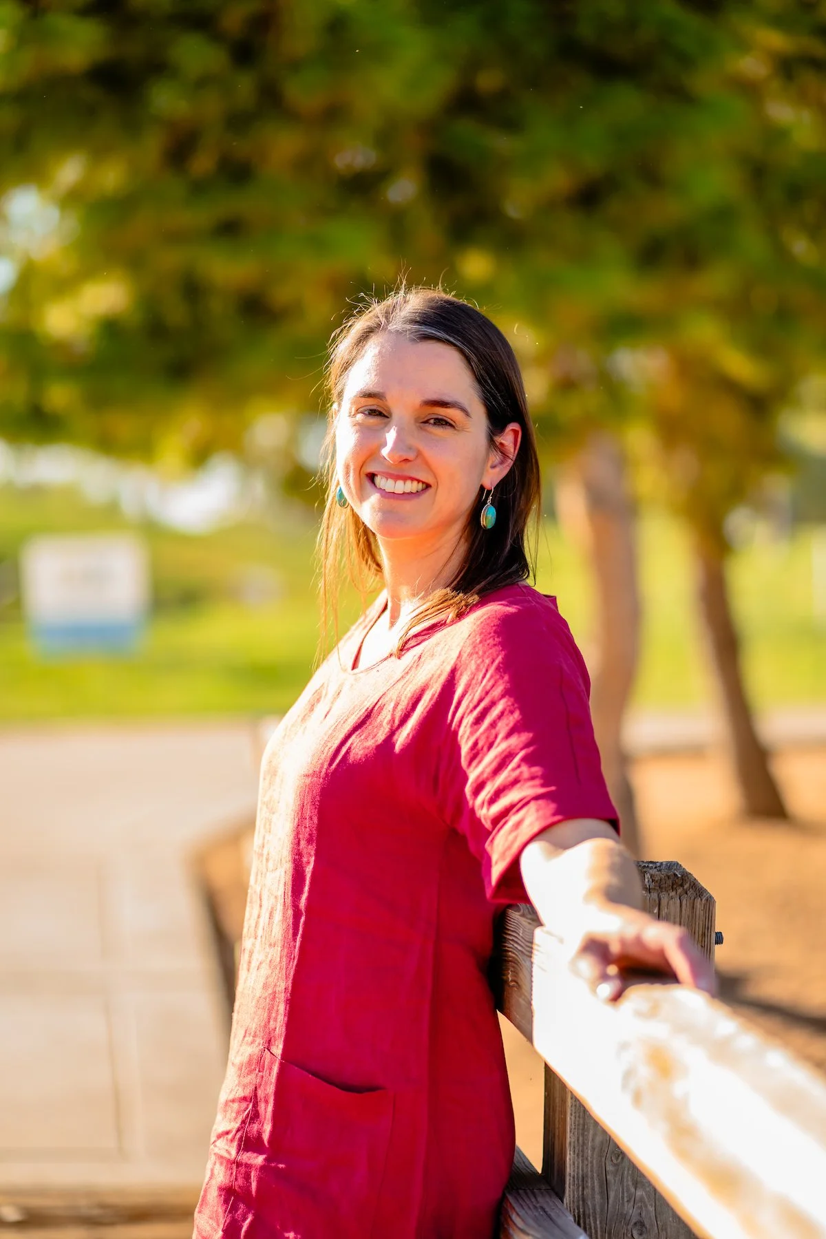 Therapist Tara Nicotra Clemente standing outside against a fence in the sunlight smiling