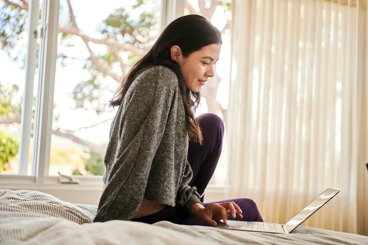 Woman on bed engaged in online therapy from Newton Massachusetts