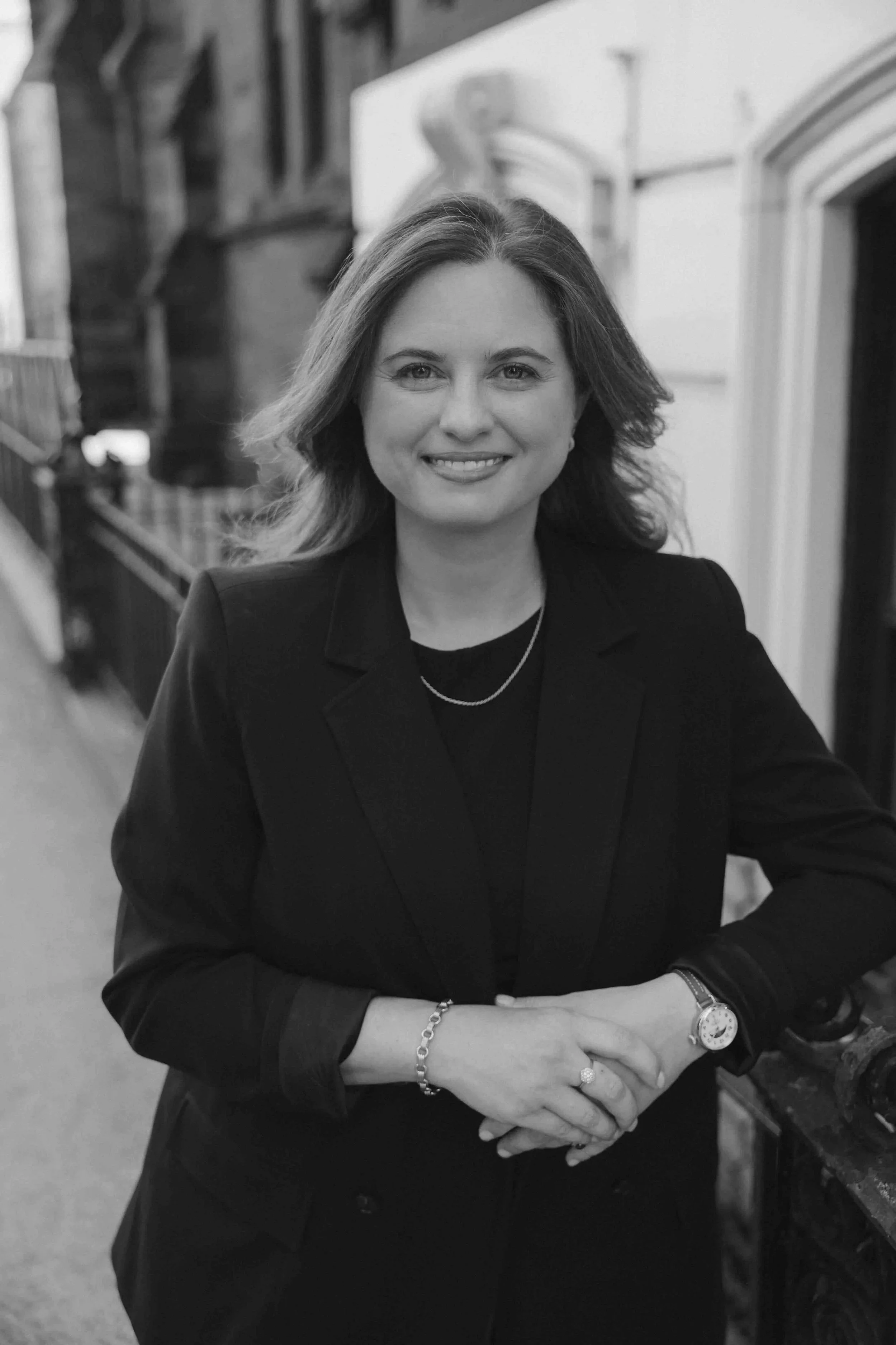 Black and white image of woman in our forties in corporate attire outside.