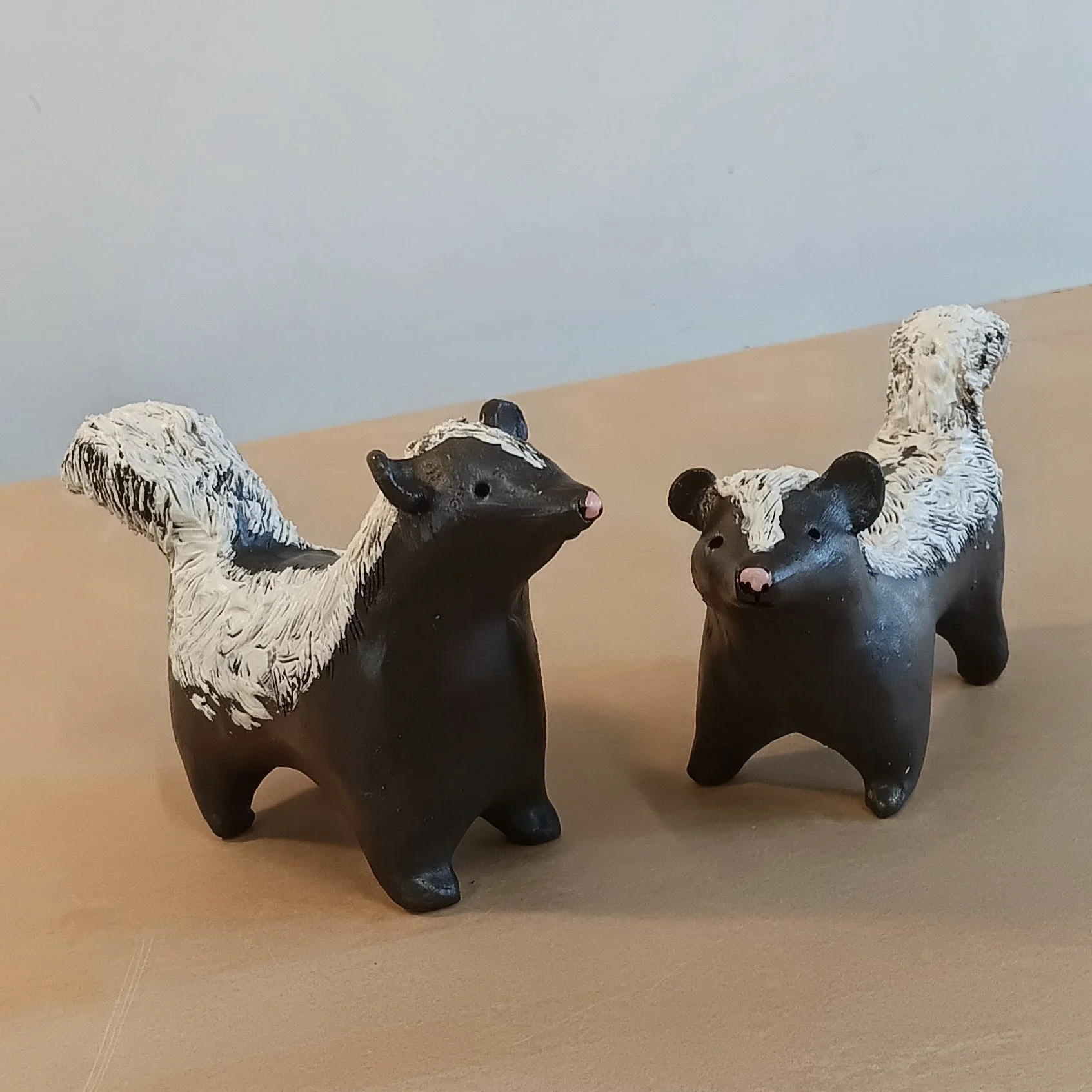 Skunks, black earthenware clay with white slip, clear acrylic spray finish