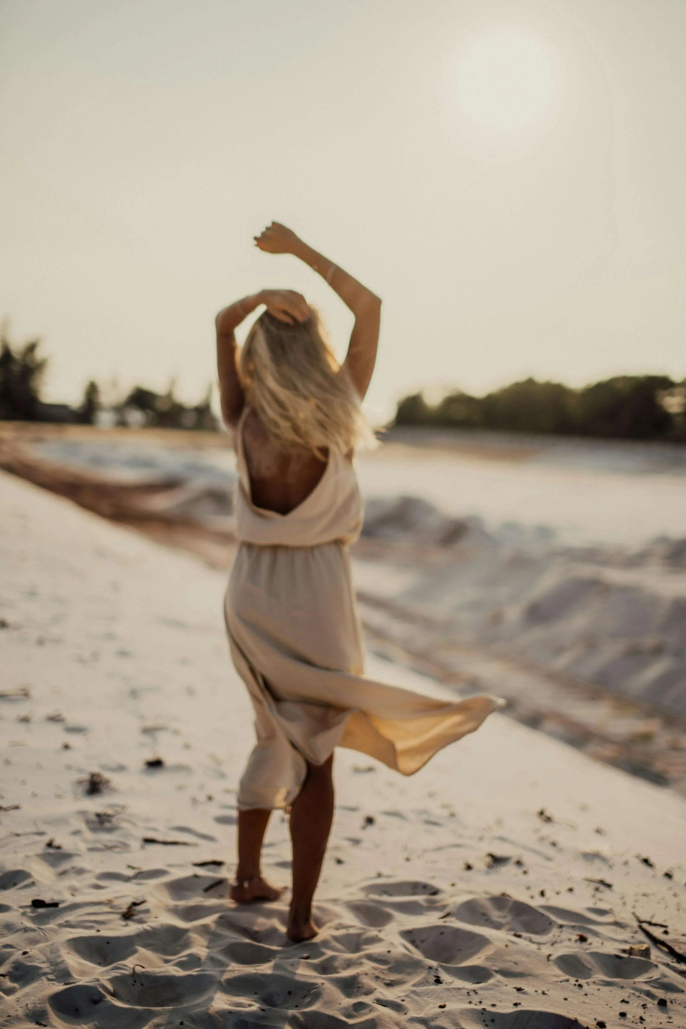 a woman in a loose linen dress dancing on the beach in los angeles representing healing trauma through emdr intensives in los angeles or san francisco