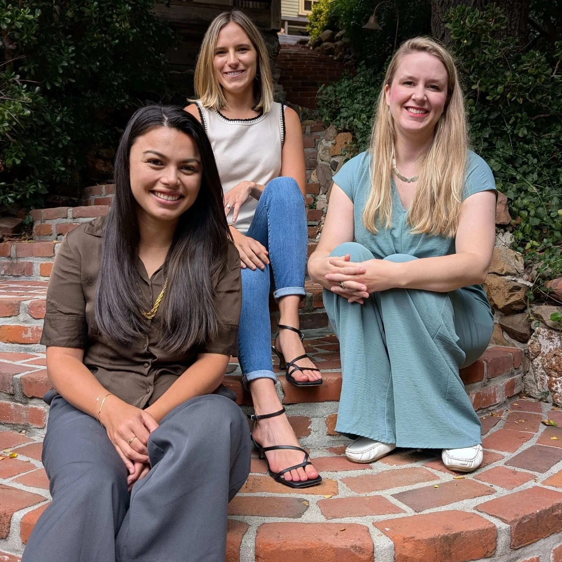 three therapists for lawyers sitting on brick steps smiling representing holistic therapy and therapy for lawyers in los angeles or san francisco