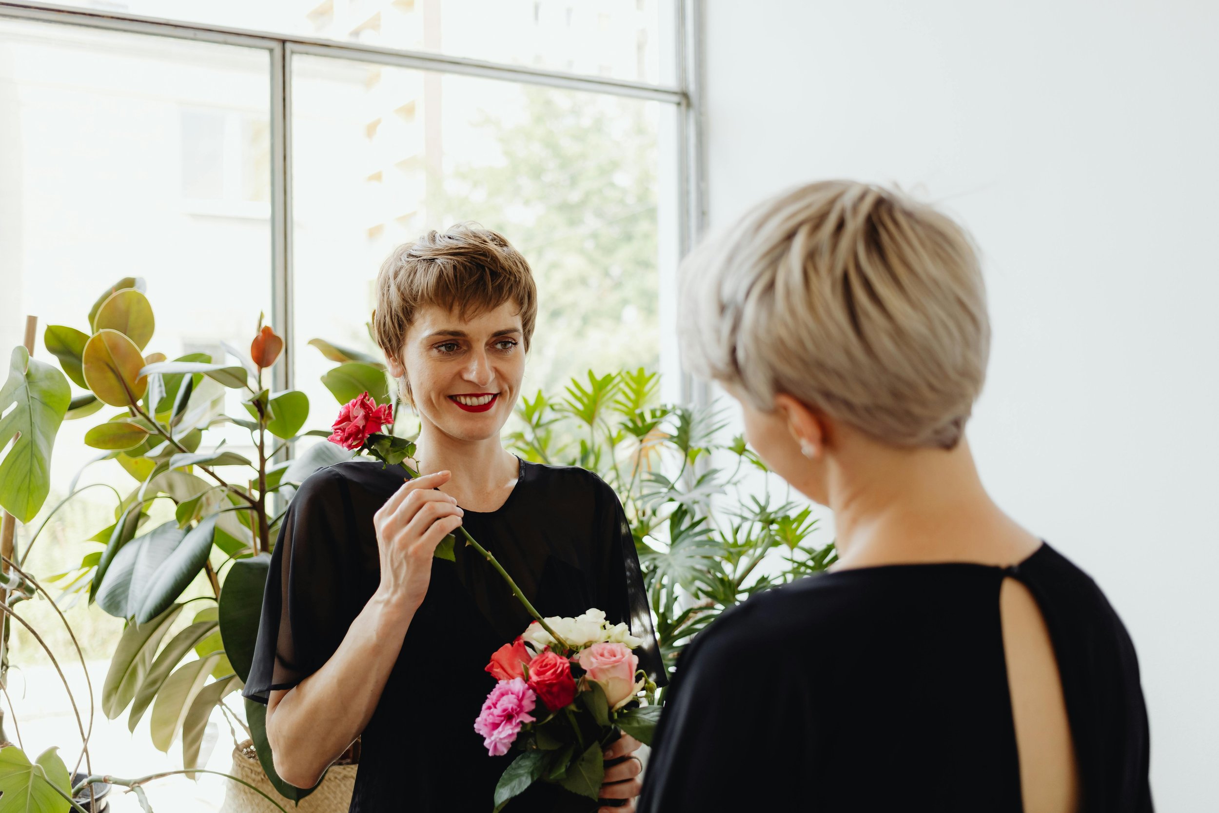 Two women giving each other flowers representing playful gestures of connection and romance on a couples date night