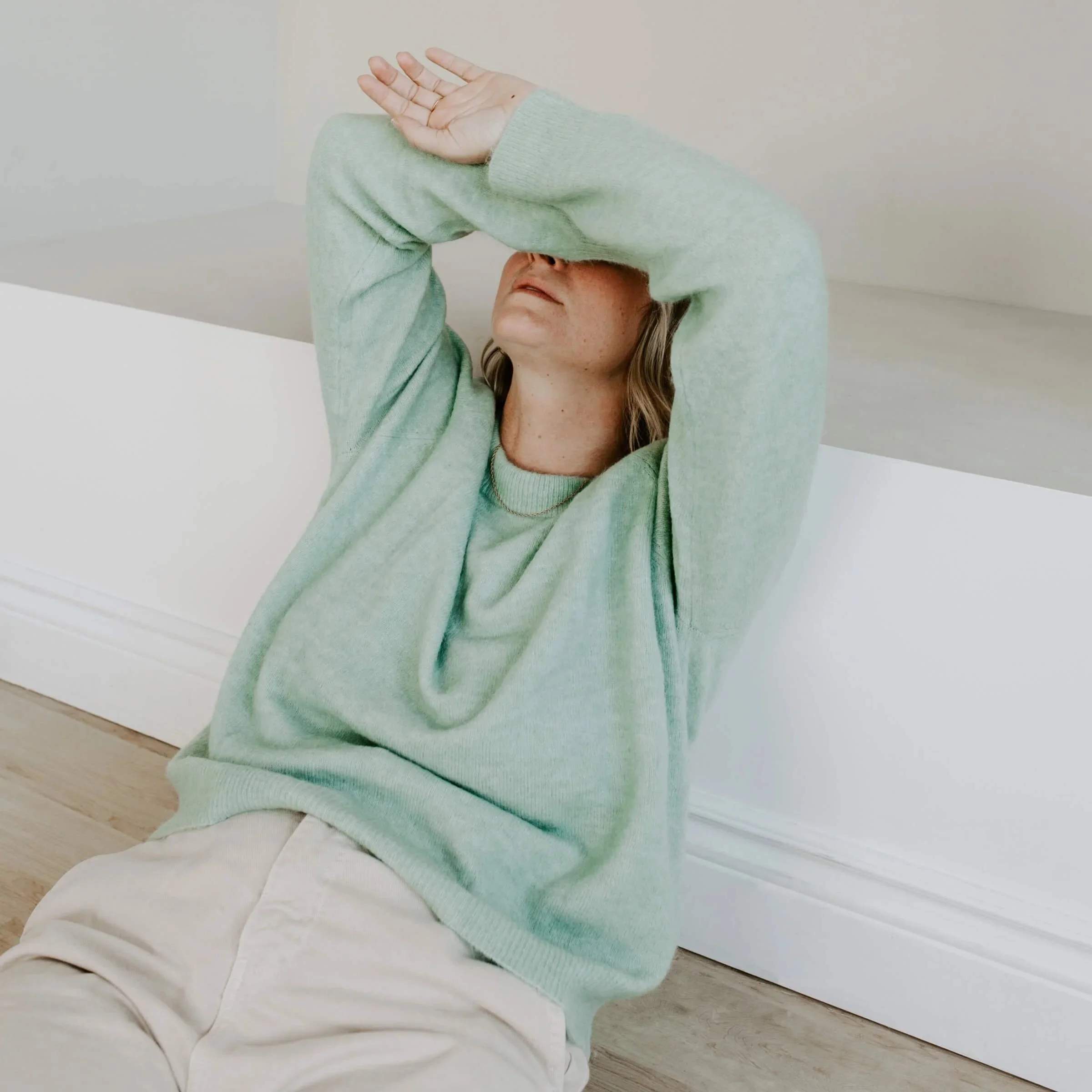 a woman in a pale green sweater holders her arms over her face representing reasons why emdr therapy works or doesn't work for people seeking emdr therapy in san franicso or los angeles
