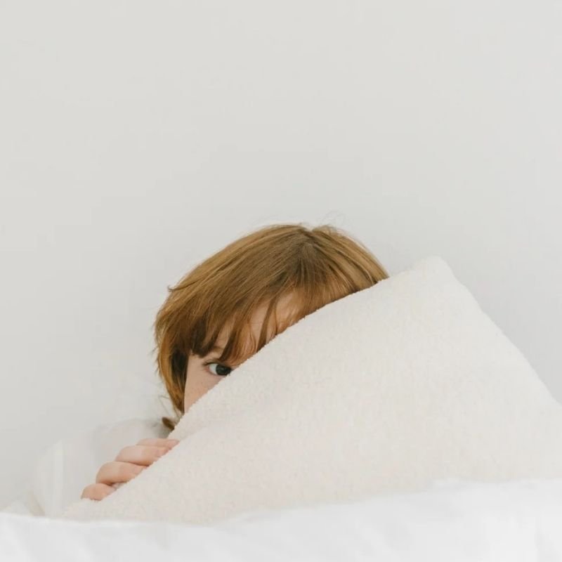 a child peeking up from behind a white pillow representing someone who has witnessed domestic violence and healed from the trauma with a los angeles emdr therapist