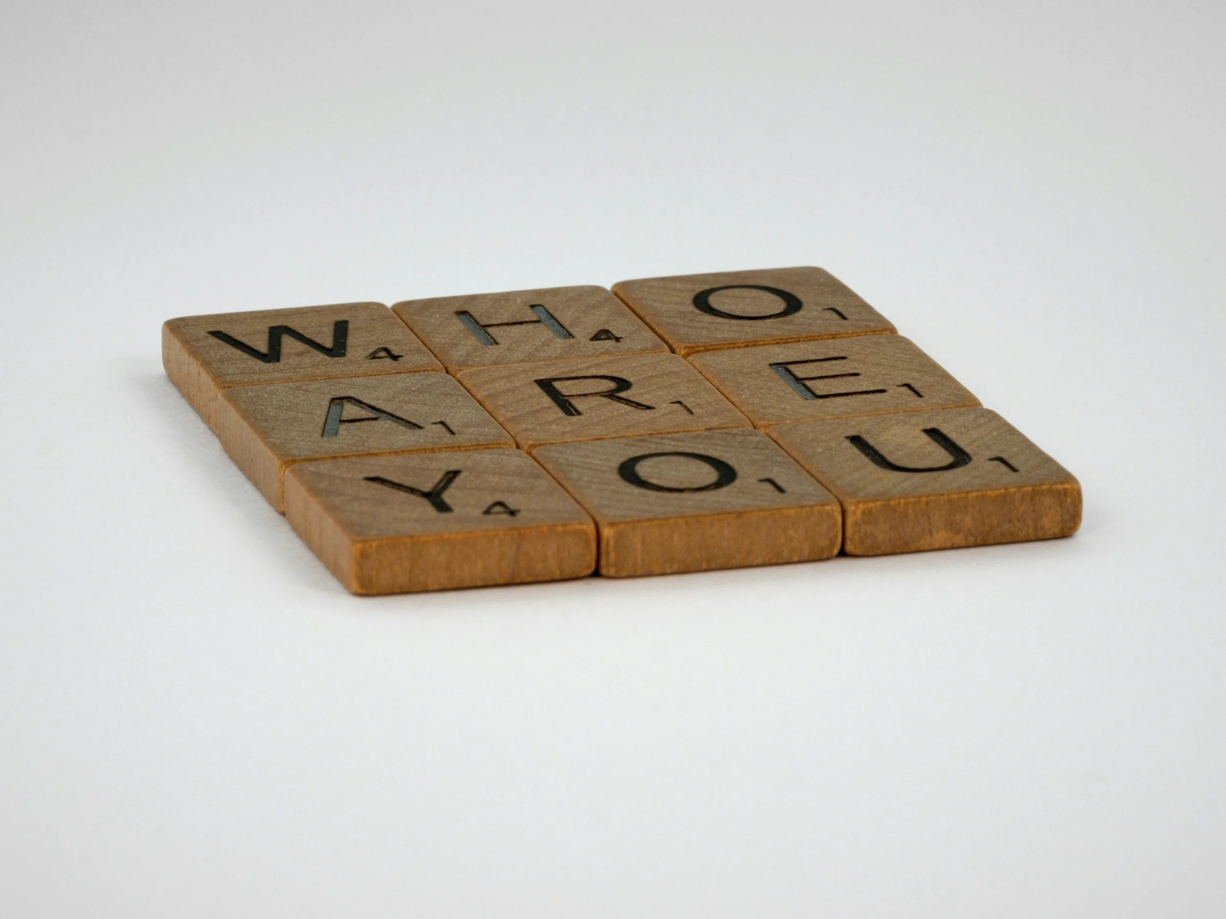 scrabble tiles spelling out the words Who Are You representing the deep trauma informed identity work that happens during Enneagram therapy