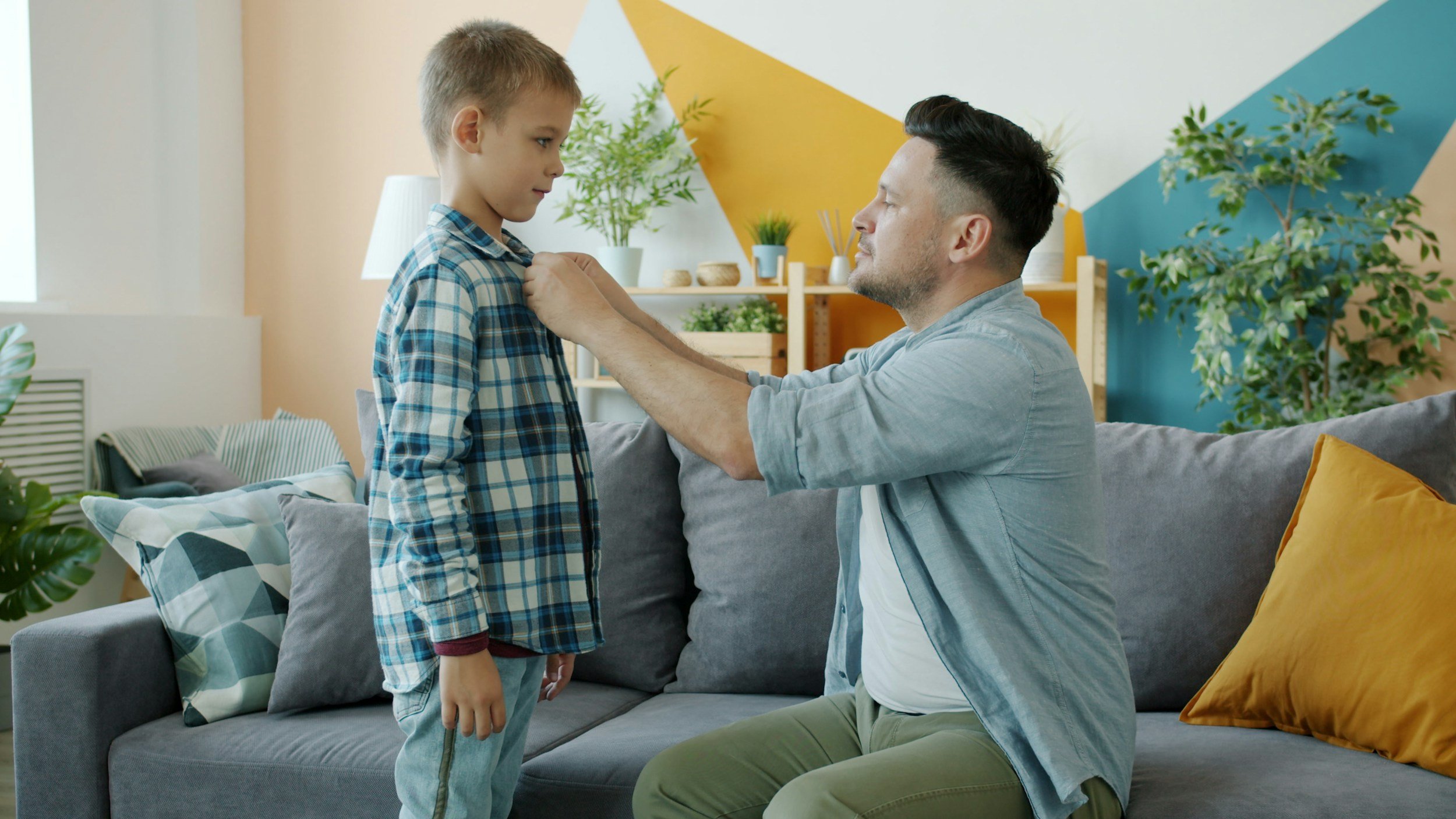 a little boy letting his father button up his shirt. A person looking grounded and self-assured, representing the quieter inner critic and greater self-trust possible through EMDR therapy for adults healing from a bullying parent