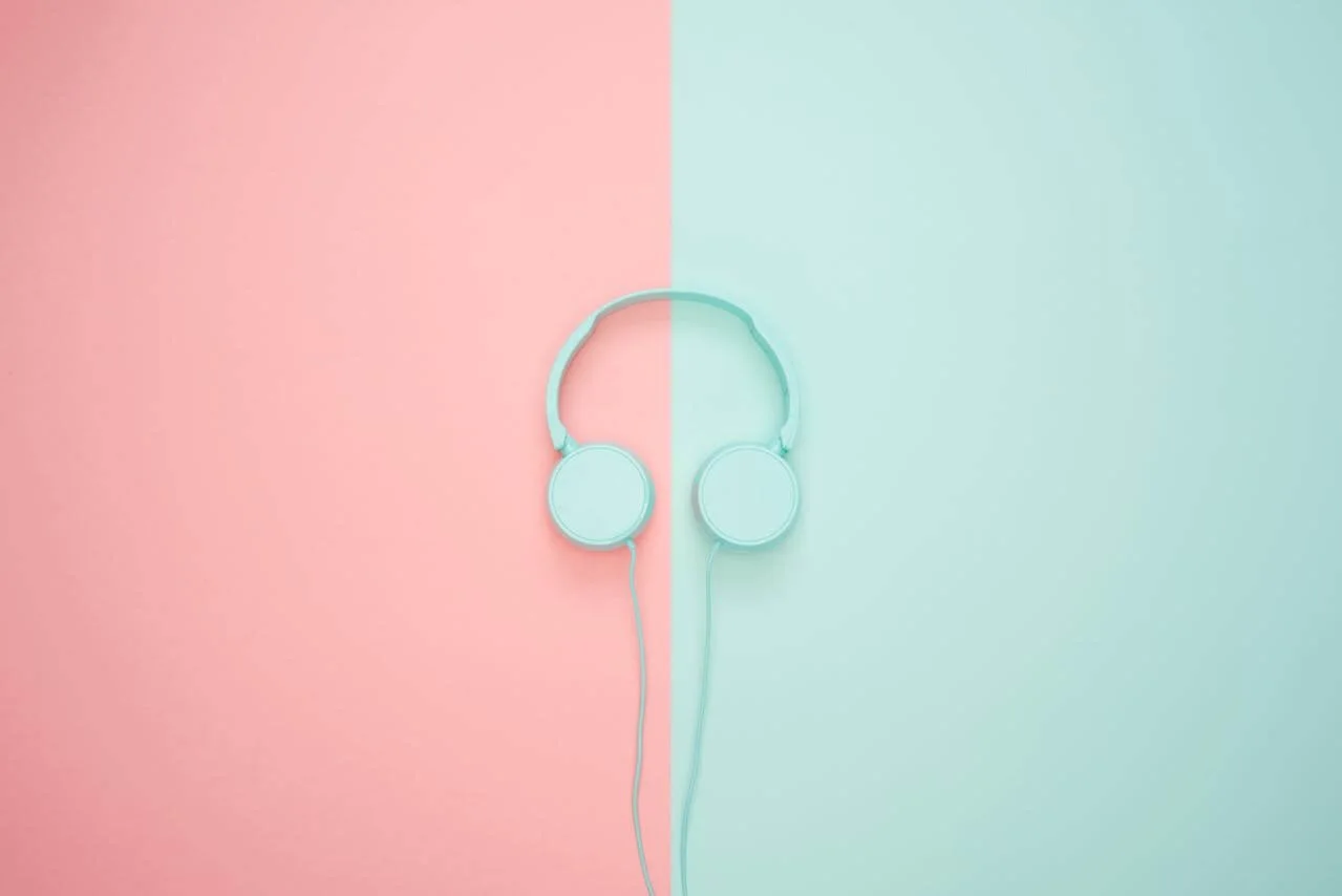 A pair of headphones over a split blue and white background, representing sensory grounding and calm supported by neurodivergent affirming therapy in California.