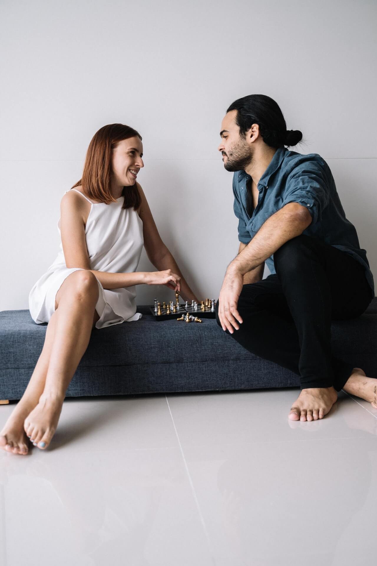 Couple playing chess and smiling, reflecting on what it means to have moved into a relationship quickly