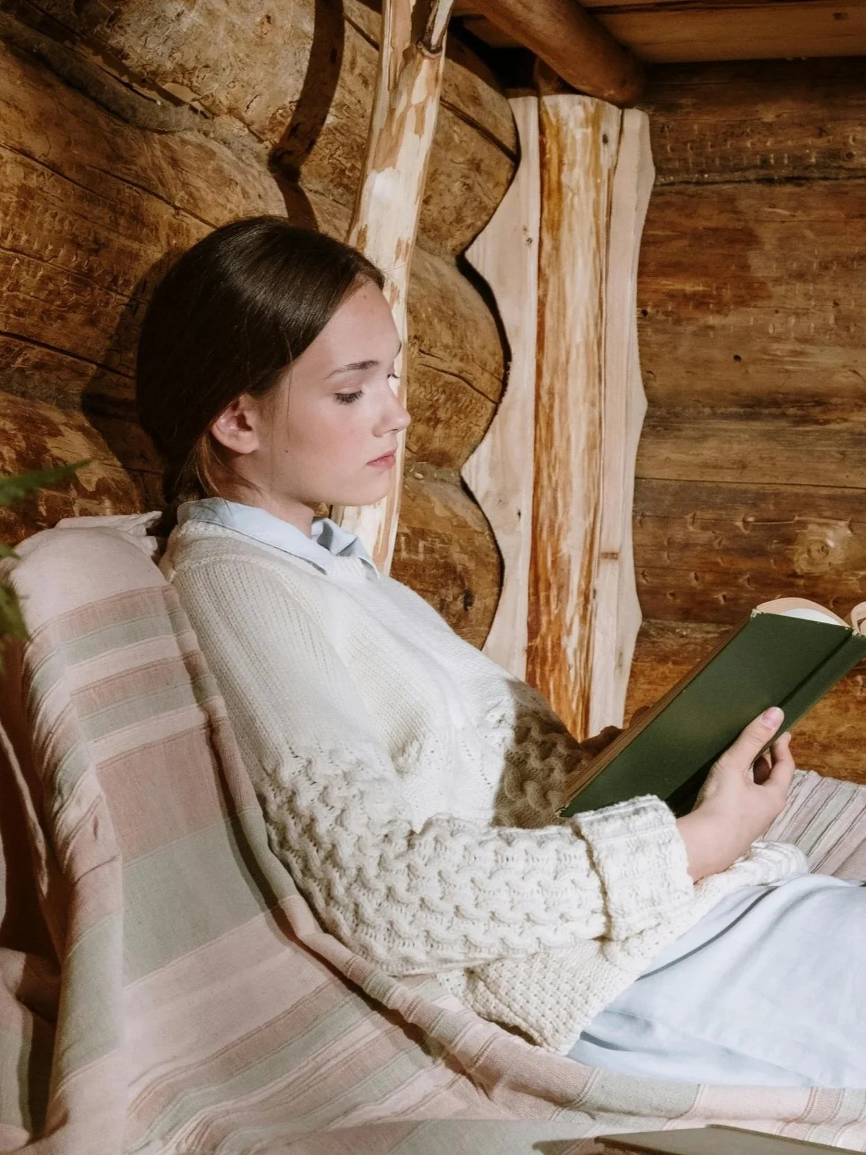 Person reading in a log cabin, representing the soft life as an intentional framework for burnout recovery