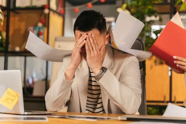 High-achieving adult looking tired at a desk representing the burnout and exhaustion of undiagnosed adult ADHD addressed in therapy in California