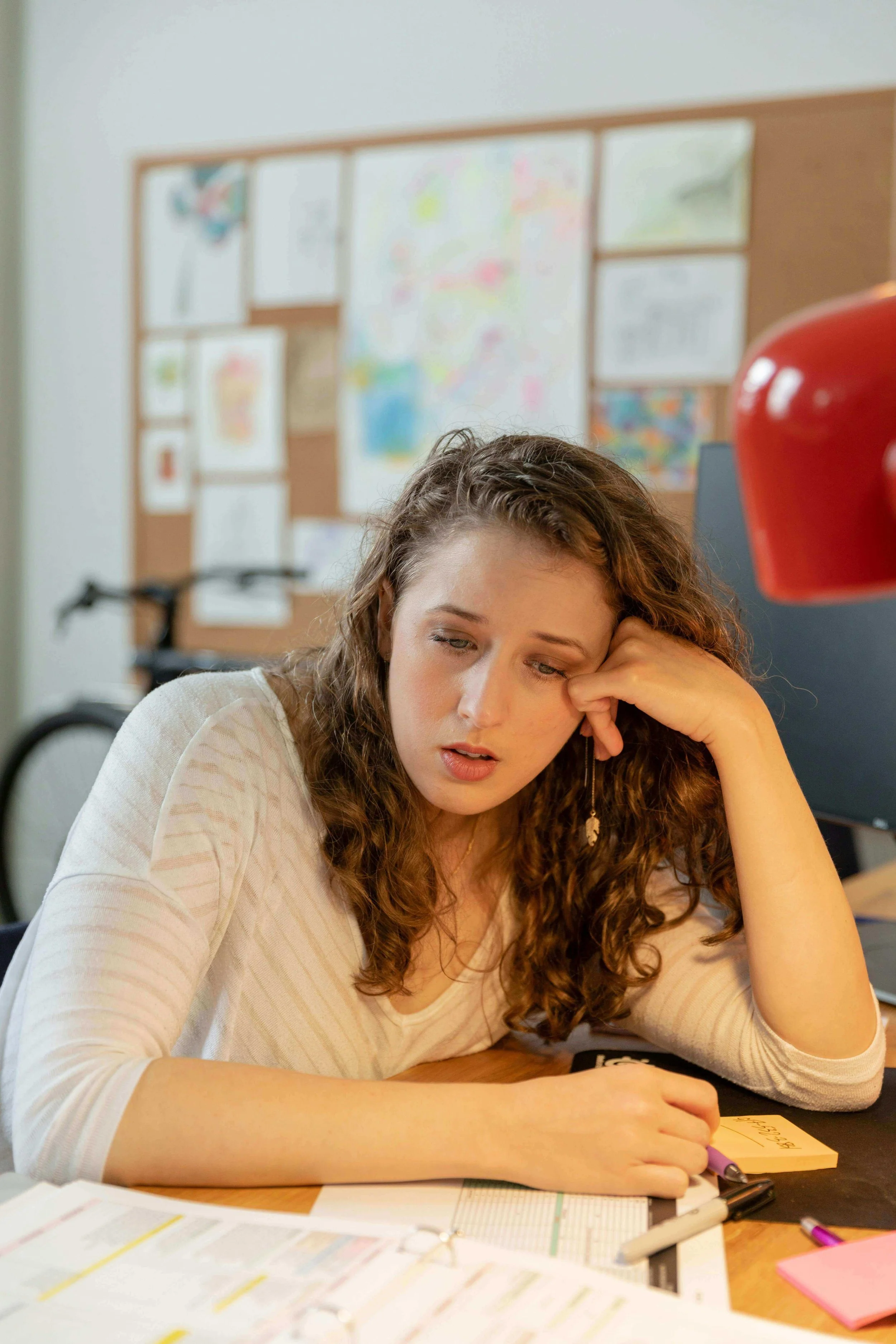 Person sitting at a desk looking at documents with a tense expression, representing financial anxiety and nervous system dysregulation addressed in holistic therapy