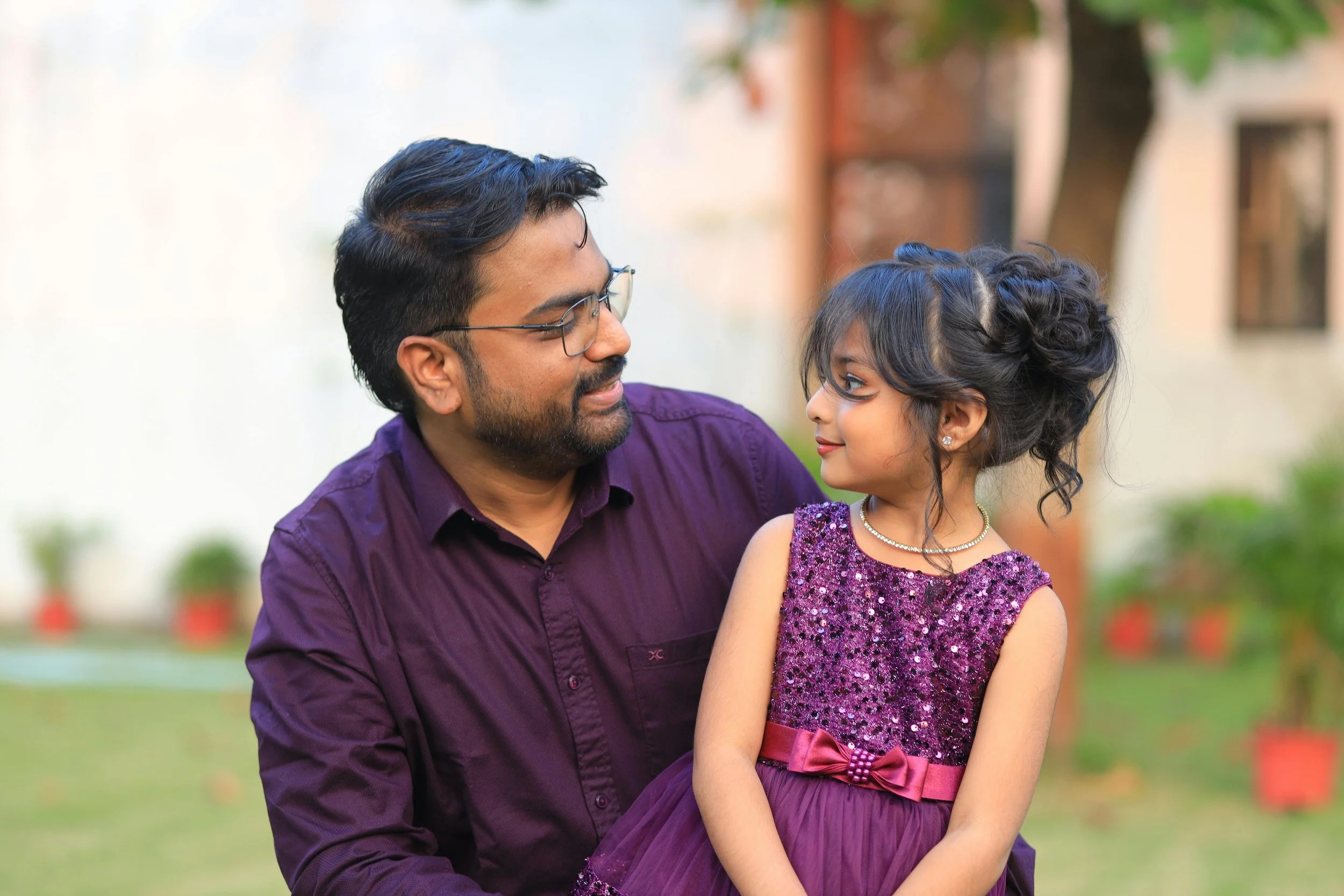 A little girl in a fancy dress that matches her dad's shirt smiling at him with openness and calm, representing the healing available through trauma therapy and EMDR for adults recovering from complex trauma rooted in early family experiences