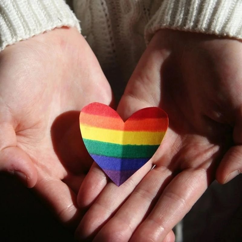 Hands holding a rainbow heart representing LGBTQ affirming therapy in Santa Cruz