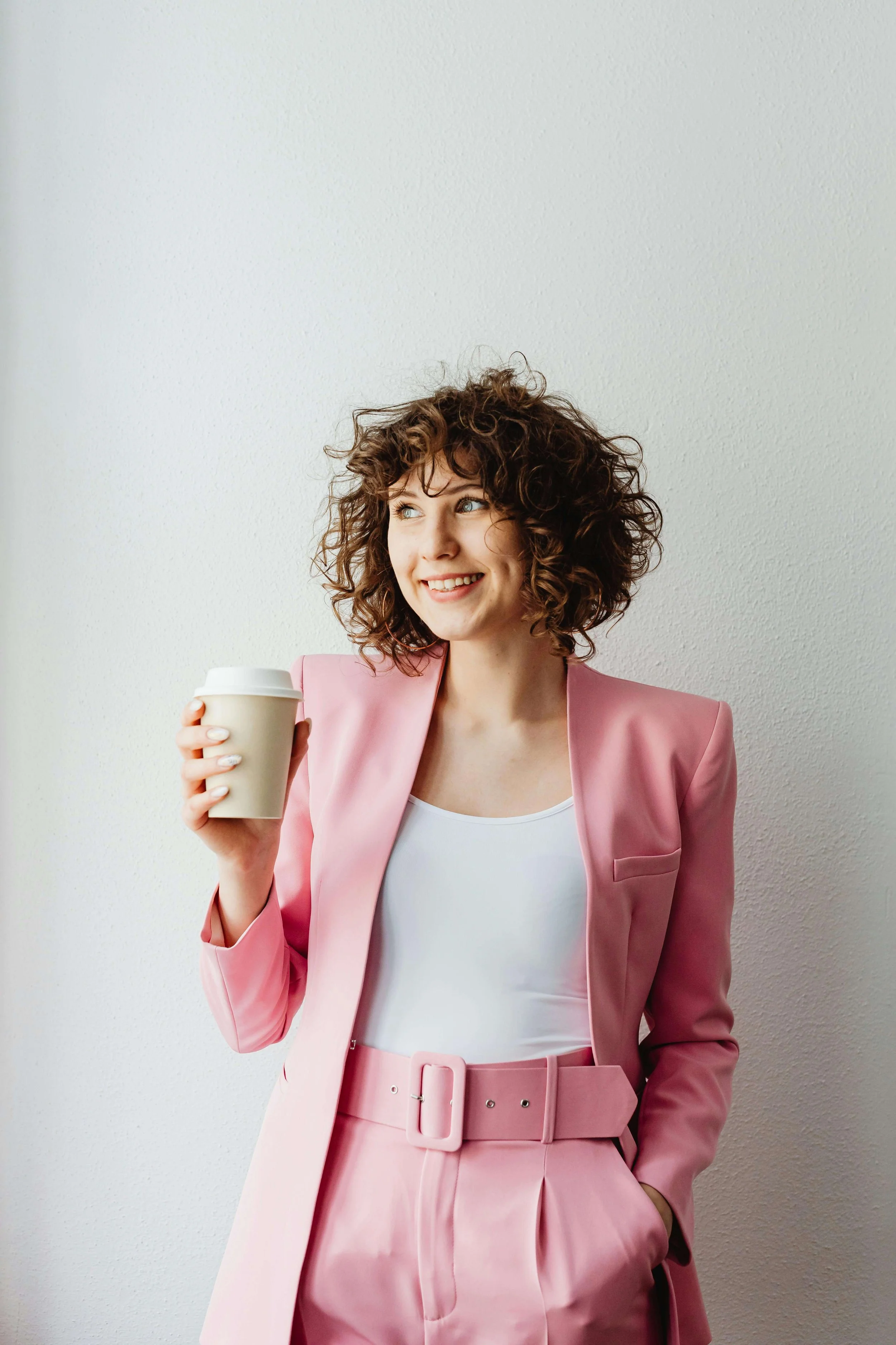 a woman smiles holding a coffee cup wearing a pink business suit representing great therapy in san francisco. we offer couples therapy san francisco and emdr therapy san francisco.