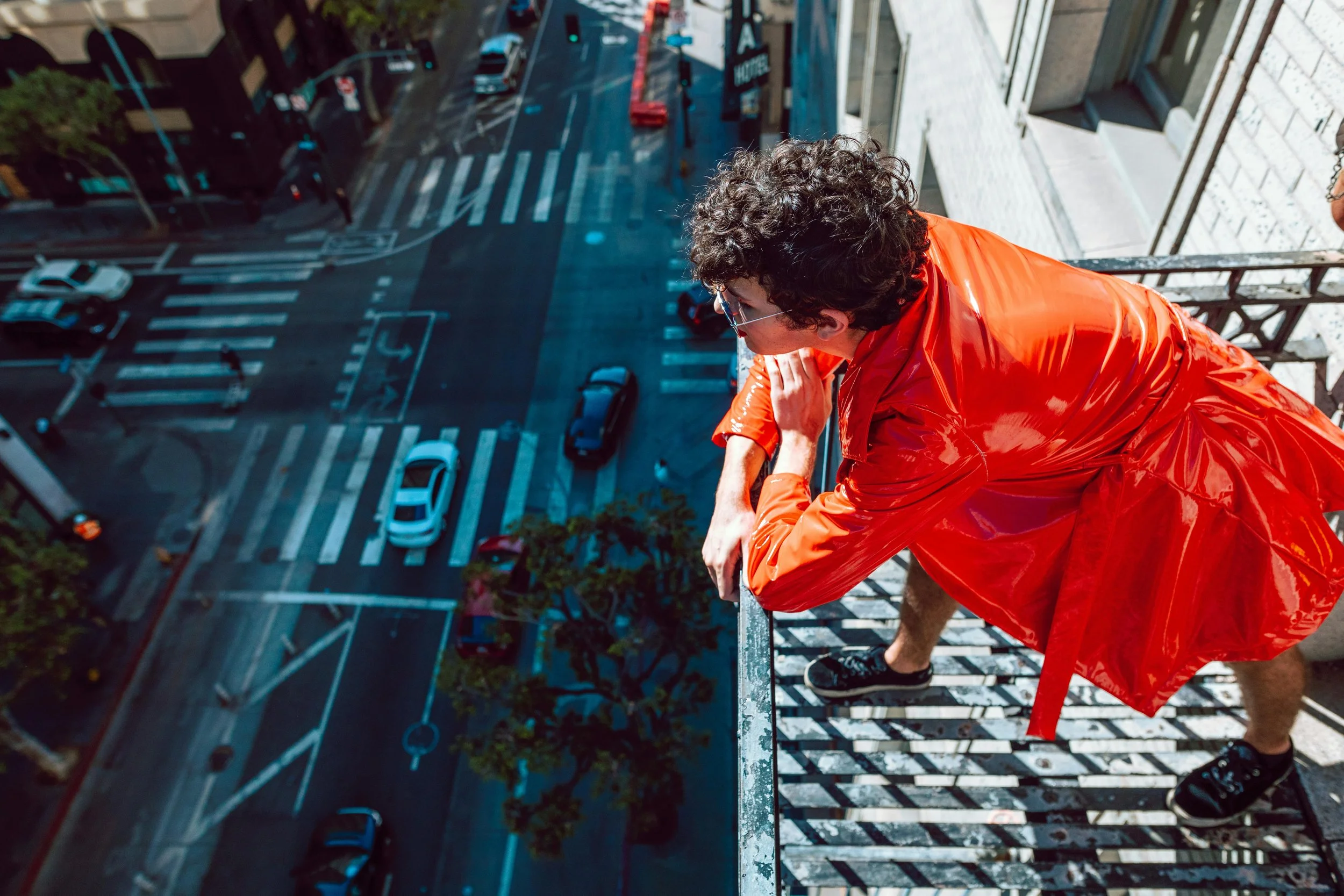 a person leaning on the rail of a fire escape overlooking an intersection in san franscisco after therapy with a lesbian therapist