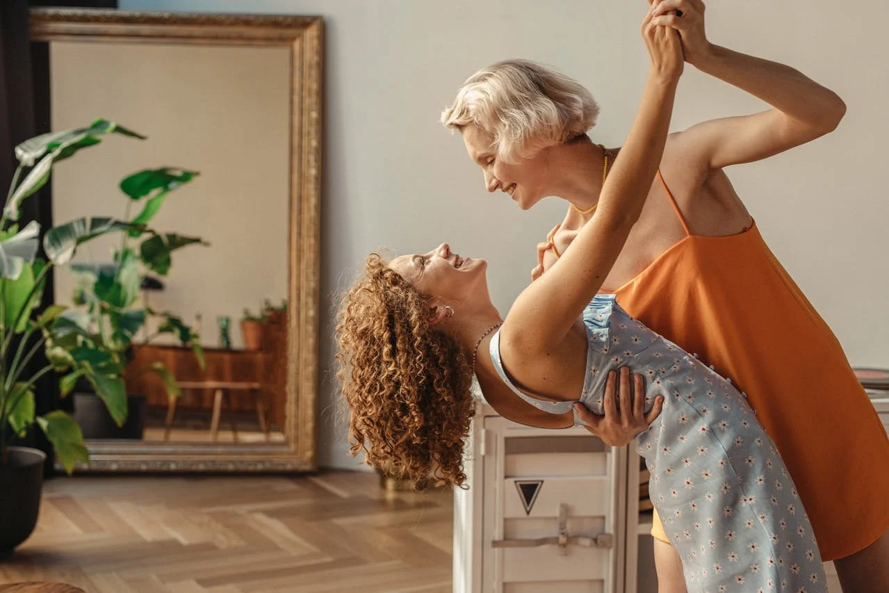 two middle aged women dancing at home representing coming out later in life and how working with a lesbian therapist can support your identity journey