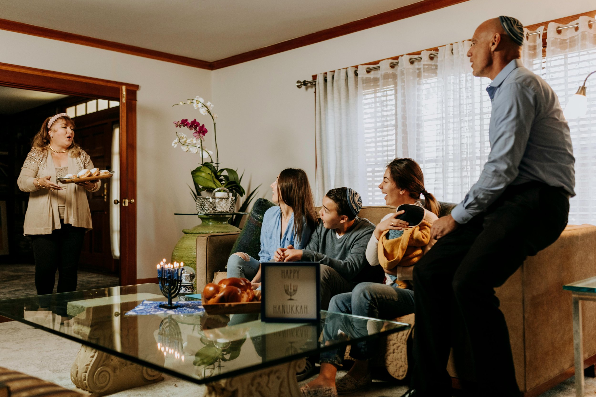 a family looking at a woman bringing in a plate of cupcakes. Schedule a free consultation for EMDR therapy or couples therapy at Laurel Therapy Collective to address anxiety about in-laws throughout California and Florida