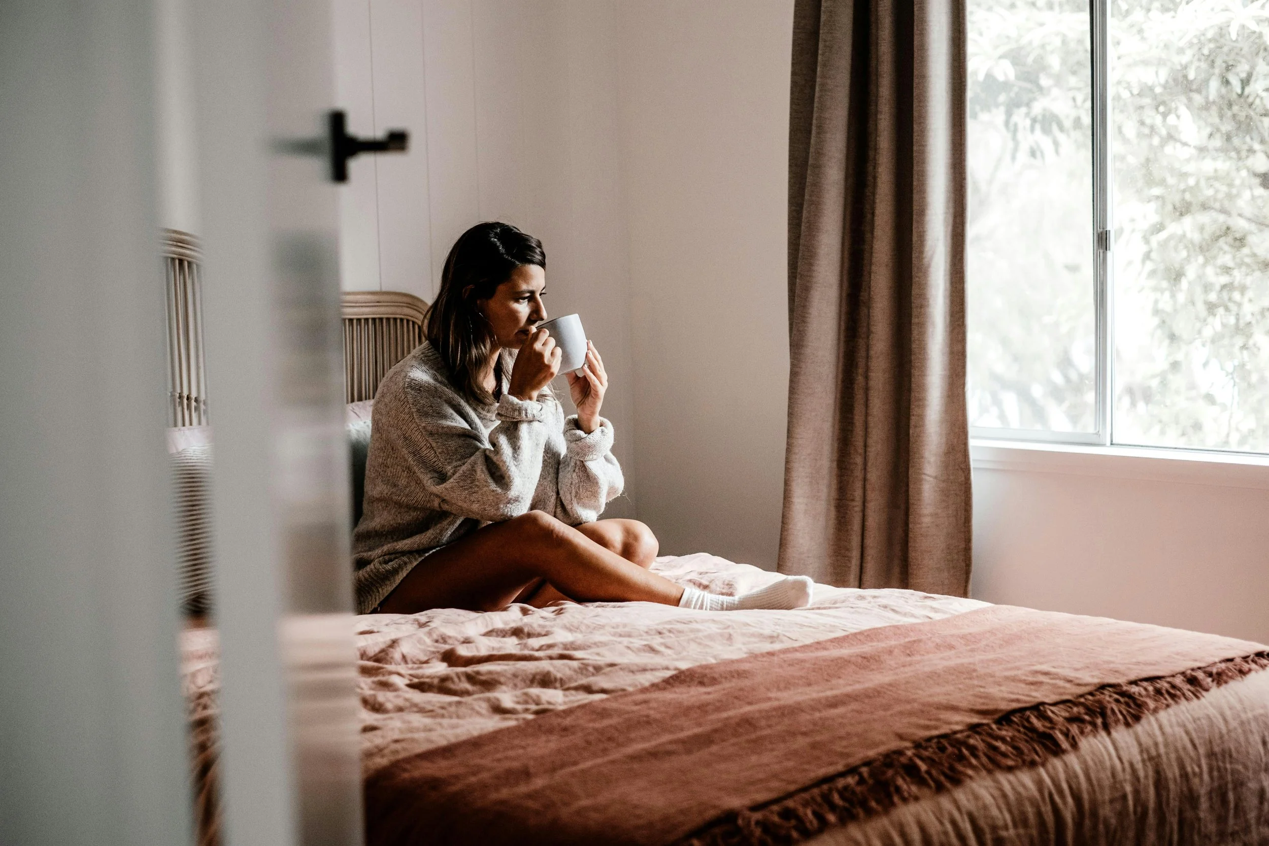 Person drinking tea contentedly at home representing nervous system rest and holistic therapy in San Francisco