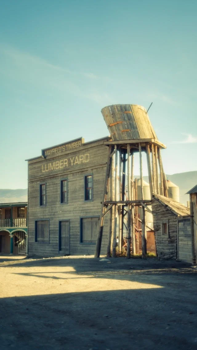 frontier landscape with lumber yard and water tower train station, representing the Wild West era of AI in mental healthcare from a trauma therapist's perspective