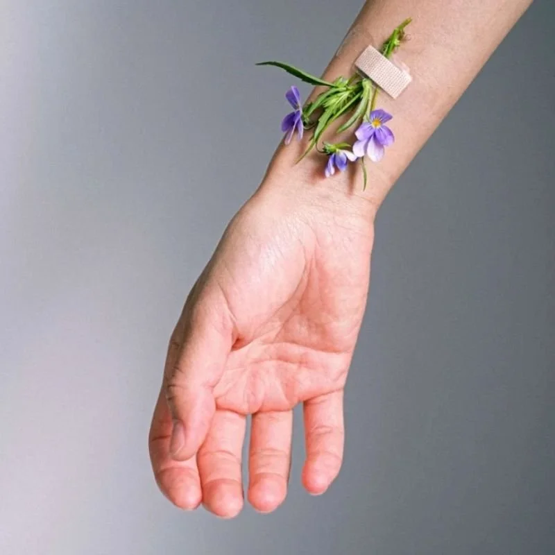 an image of a woman's arm outstretched with a cluster of flowers taped to her wrist representing someone who has healed from medical trauma through trauma therapy with a los angeles EMDR therapist