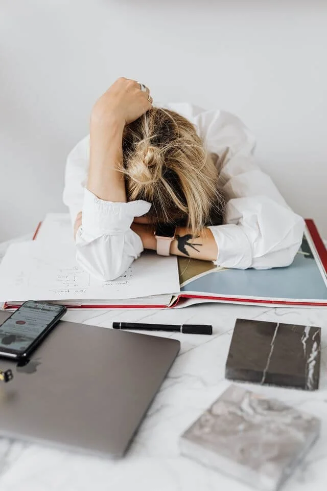 Adult looking distracted and overwhelmed at a desk representing the experience of undiagnosed ADHD and holistic therapy support in California