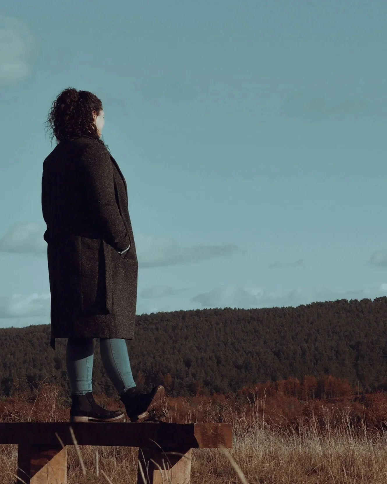 A person wearing a long coat walking in nature, representing the intrusive replaying that EMDR therapy is designed to help with