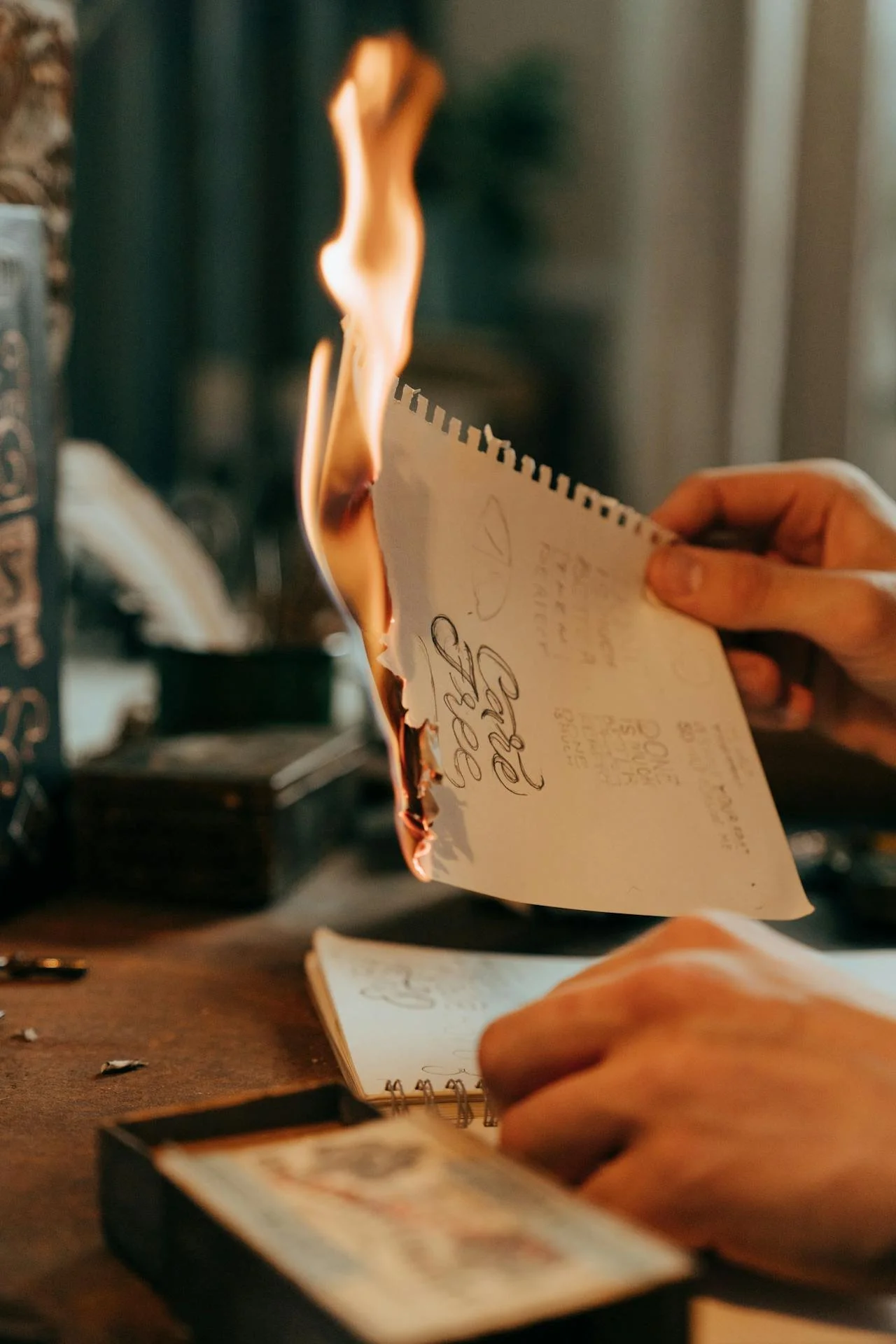 a piece of paper burning in someone's hand representing writing a letter to the person who broke your heart and burning it as a way to get closure. our therapists are here to help you process.