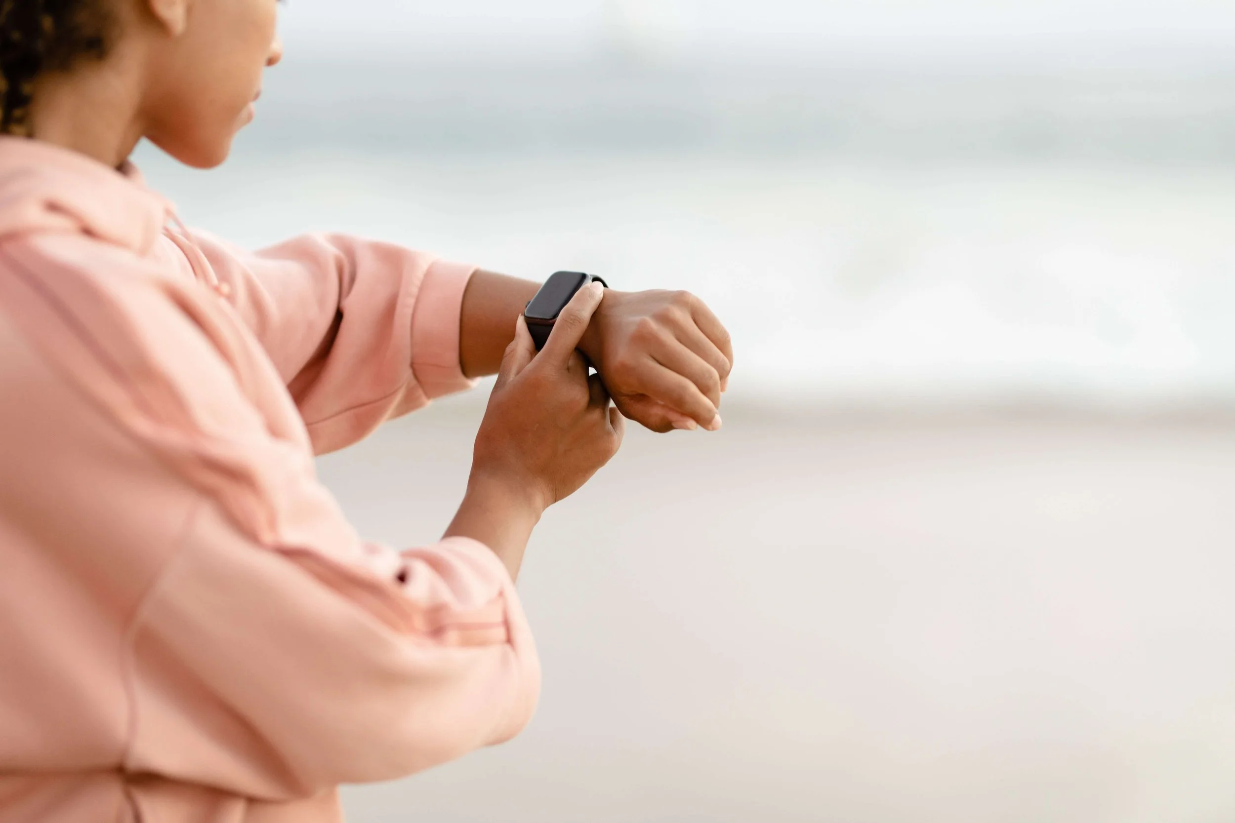 Person checking a fitness tracker with a tense expression representing health tracking anxiety and nervous system dysregulation addressed in holistic therapy in Los Angeles