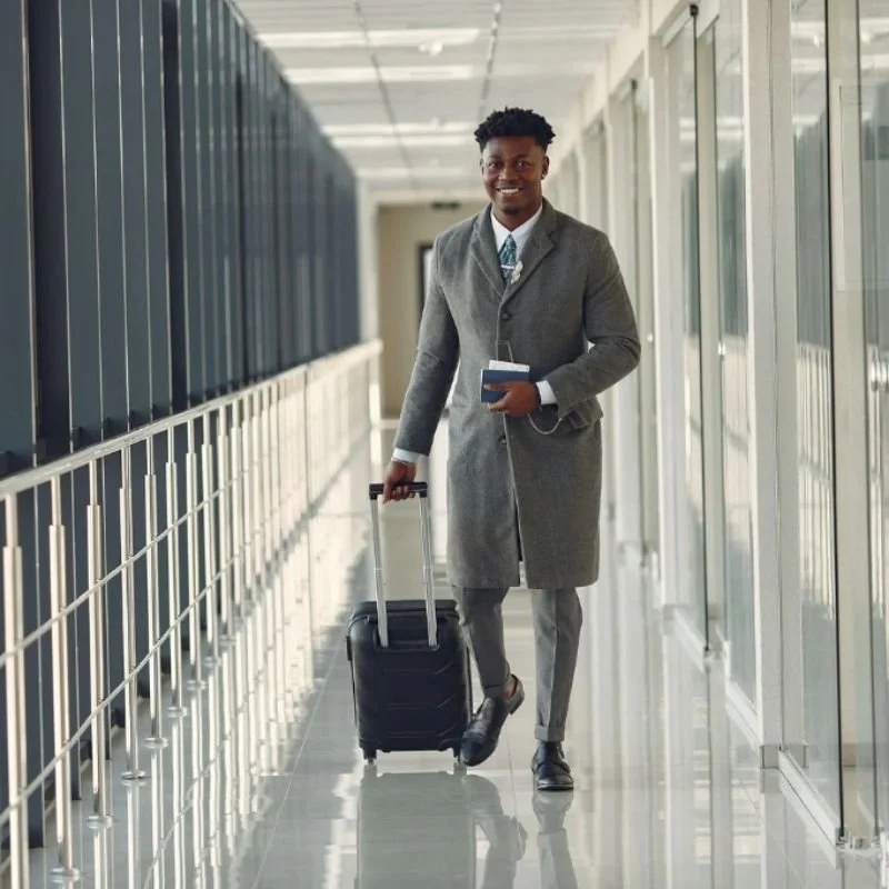 a smiling man rolling a suitcase down an airplane boarding tunnel representing someone who has overcome a phobia with EMDR therapy los angeles