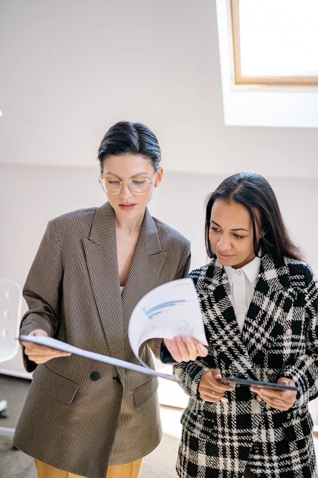 Two women creatives looking at a brief together representing collaborative performance review discussions in creative and professional workplaces