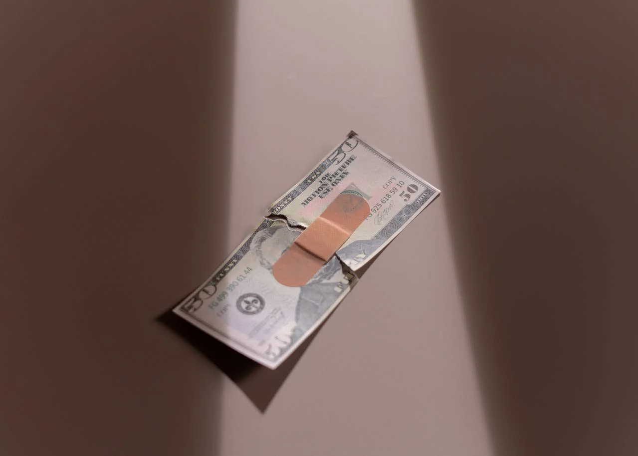 a 50 dollar bill ripped in half taped back together with a bandaid representing healing conflict about money through couples therapy in los angeles