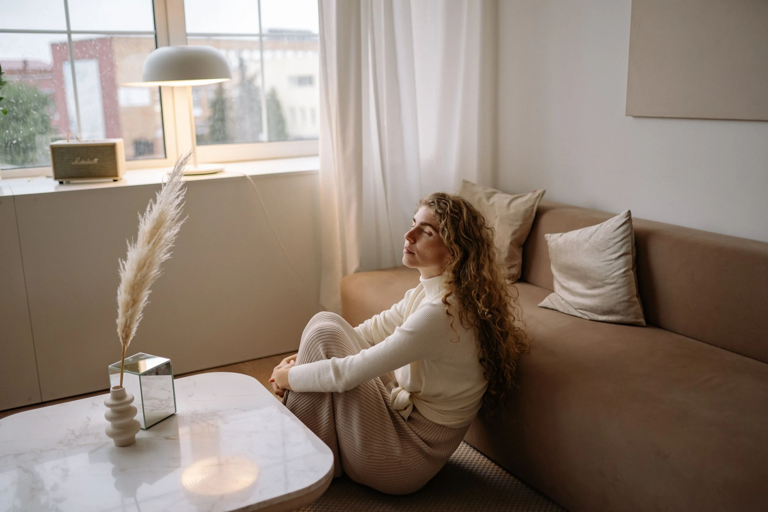 Woman meditating in her living room representing the calm and safety needed for online EMDR therapy sessions