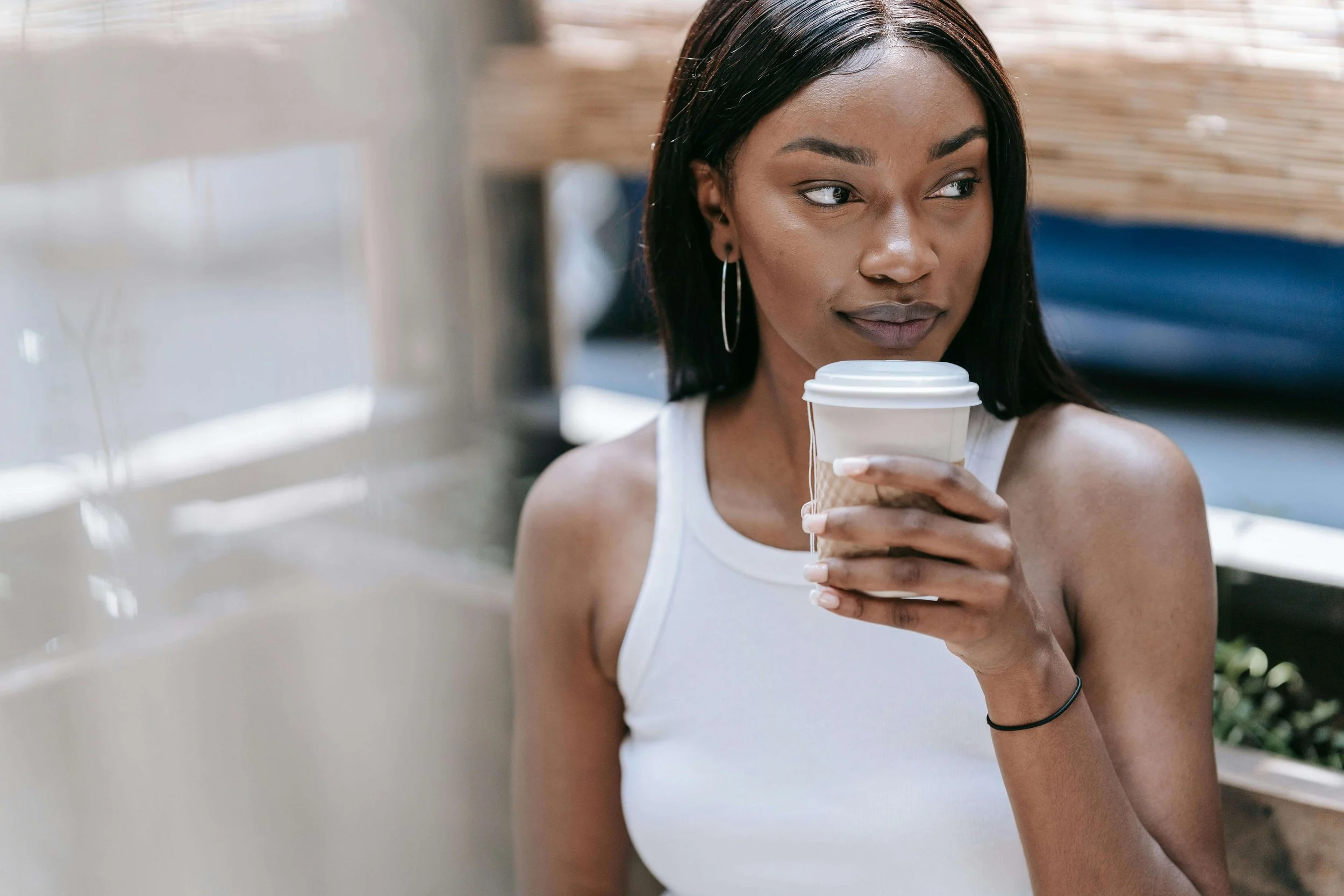 Woman relaxing with coffee and a faint smile, representing someone who feels mostly healed but still notices lingering triggers