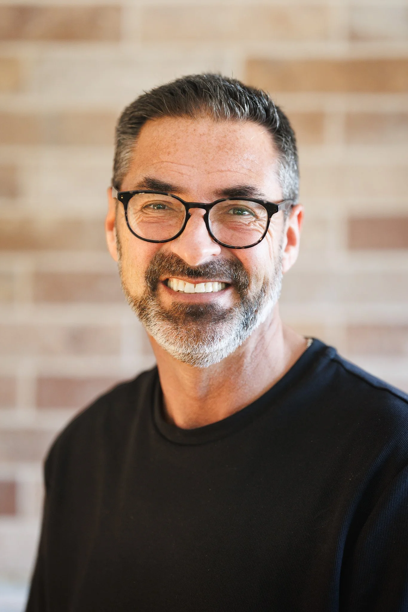 Smiling middle-aged man with glasses and a beard outdoors in fall.