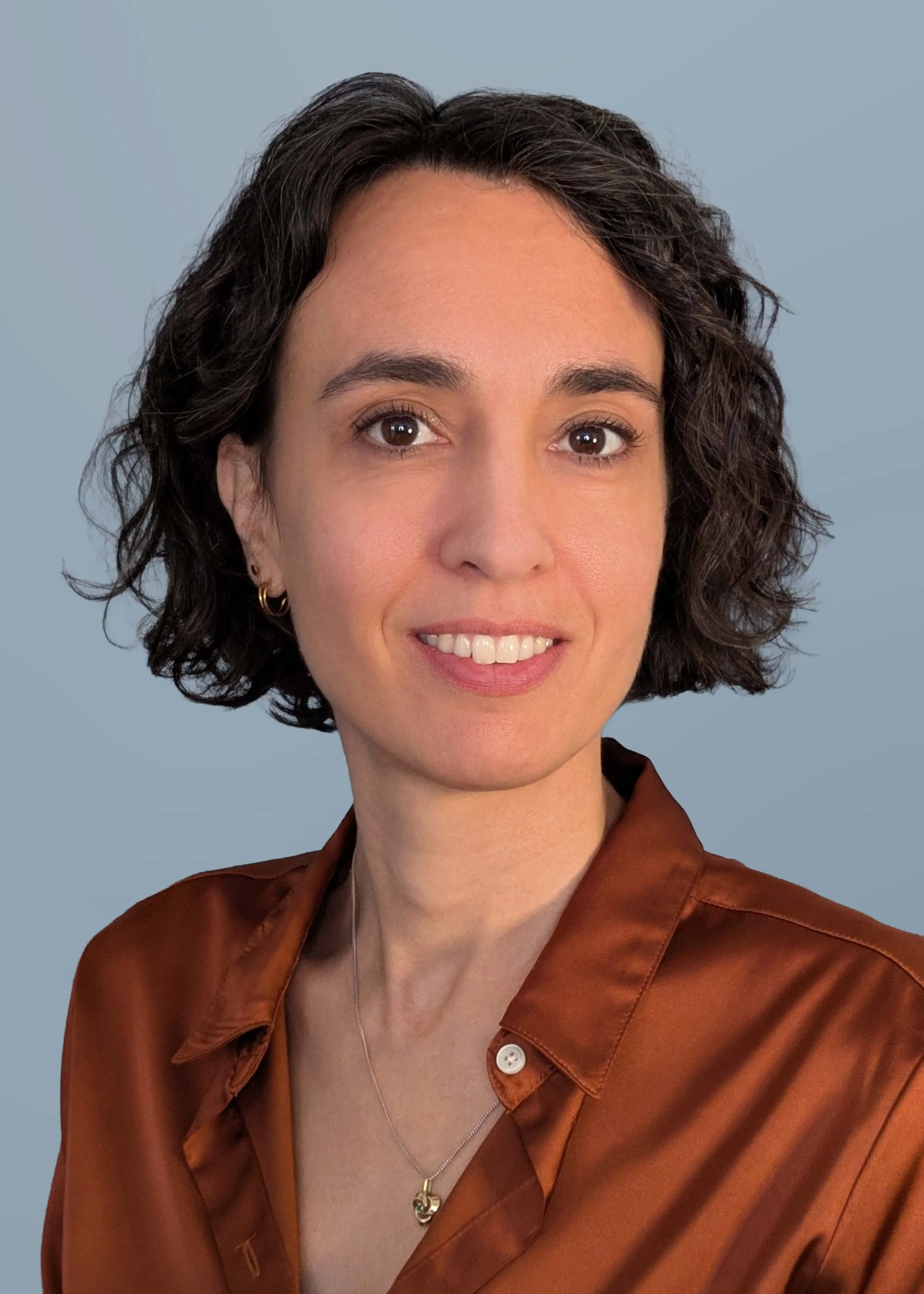 Woman in maroon shirt with short brown curly hair
