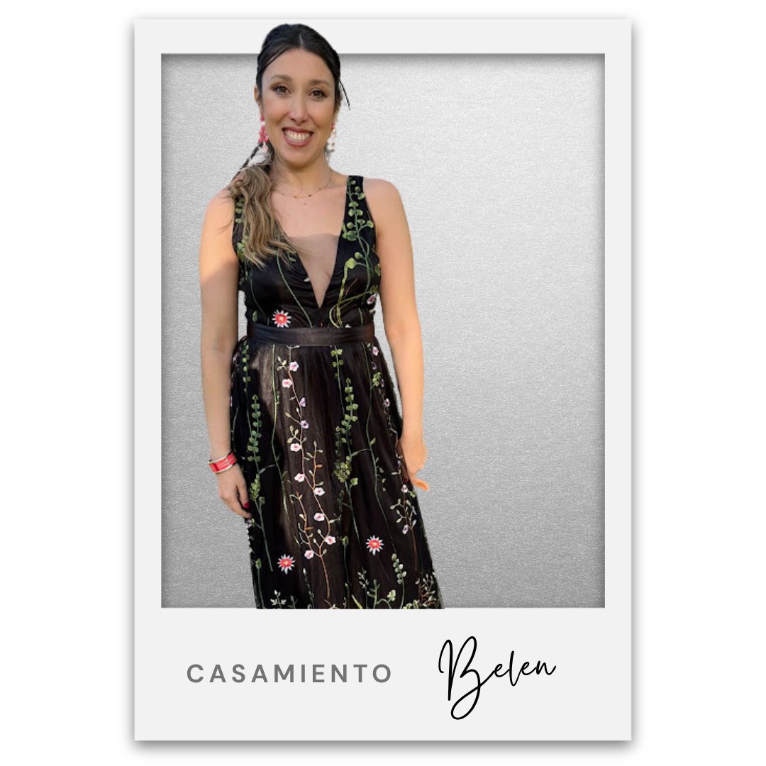 Mujer sonriendo con vestido negro con bordados florales y fondo gris. Belen Ravaza